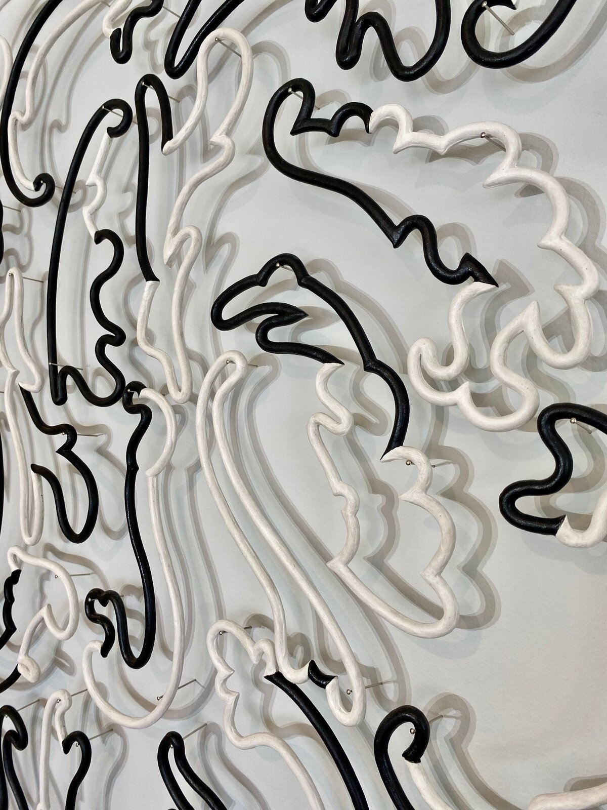 A monochrome wall installation featuring intertwined black and white scrollwork forms.