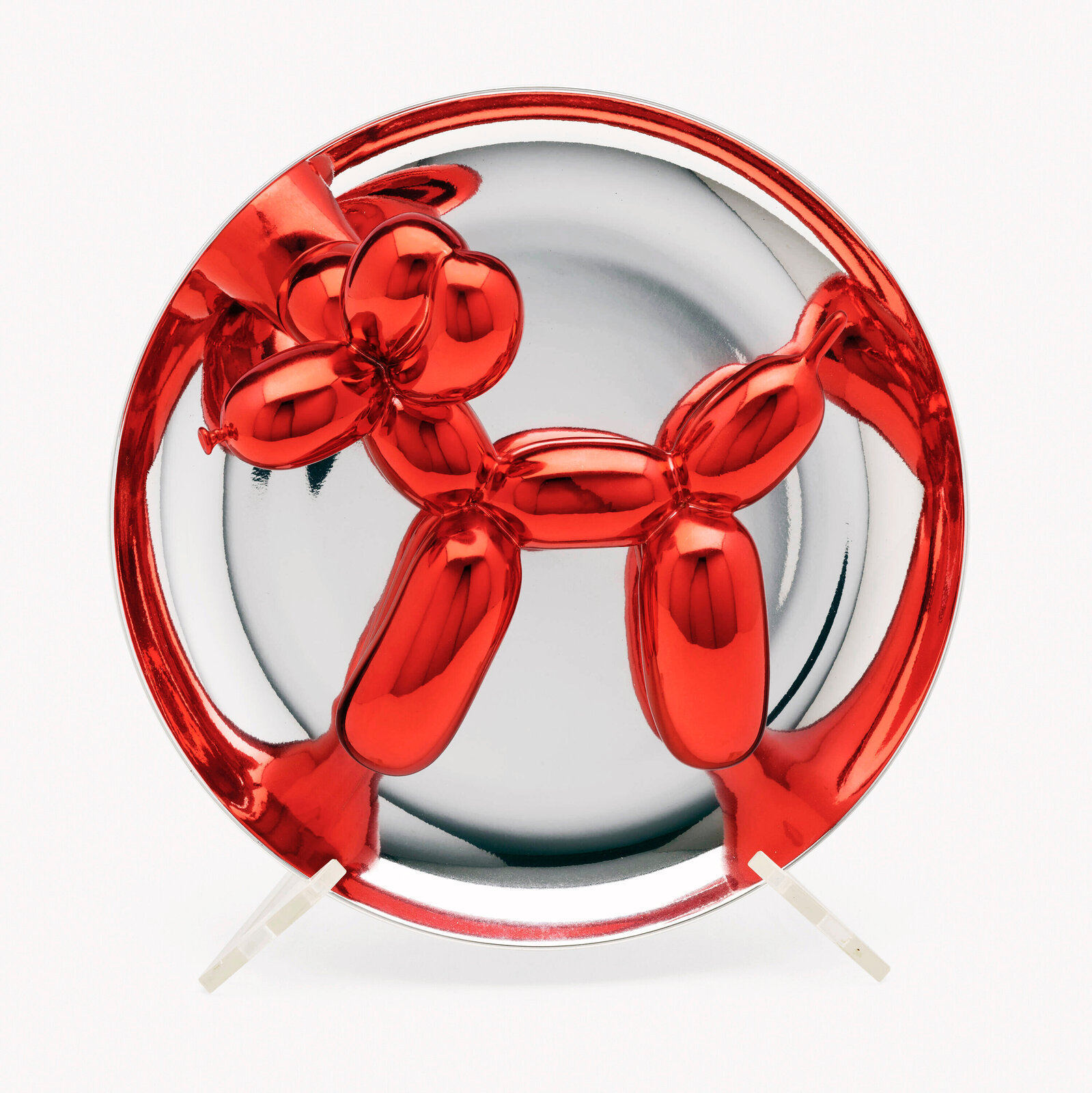 A polished red balloon-dog sculpture displayed within a reflective circular frame.