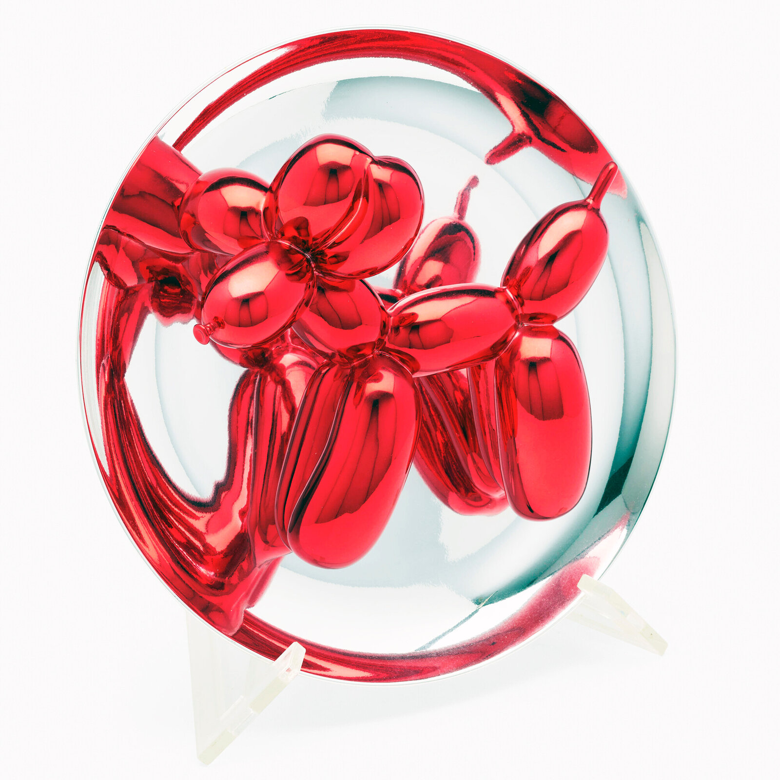 A polished red balloon-dog sculpture displayed within a reflective circular frame.