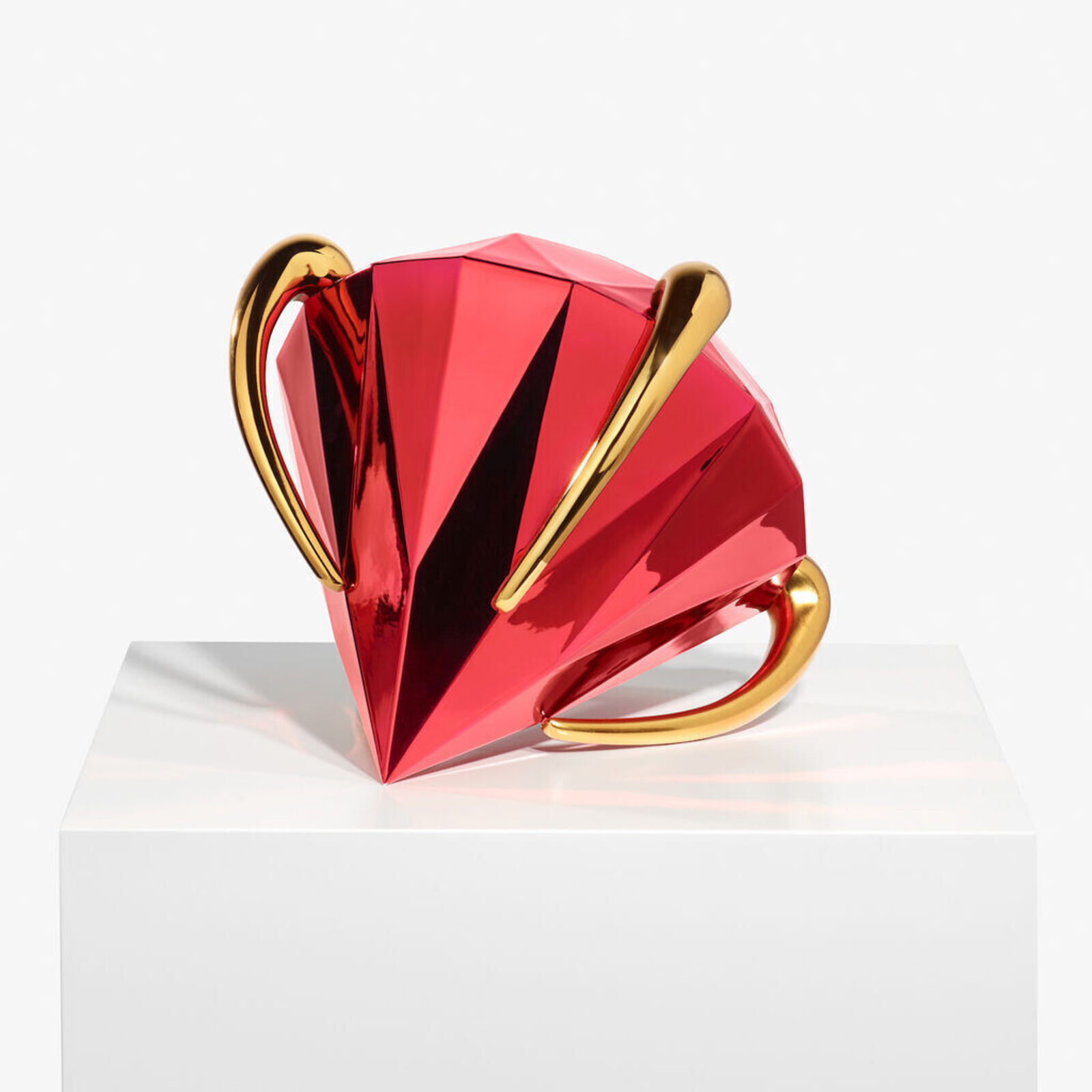 A faceted red sphere with gold accents resting on a white pedestal.