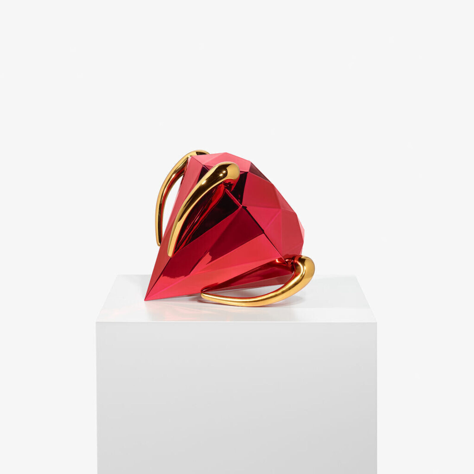 A faceted red sphere with gold accents resting on a white pedestal.