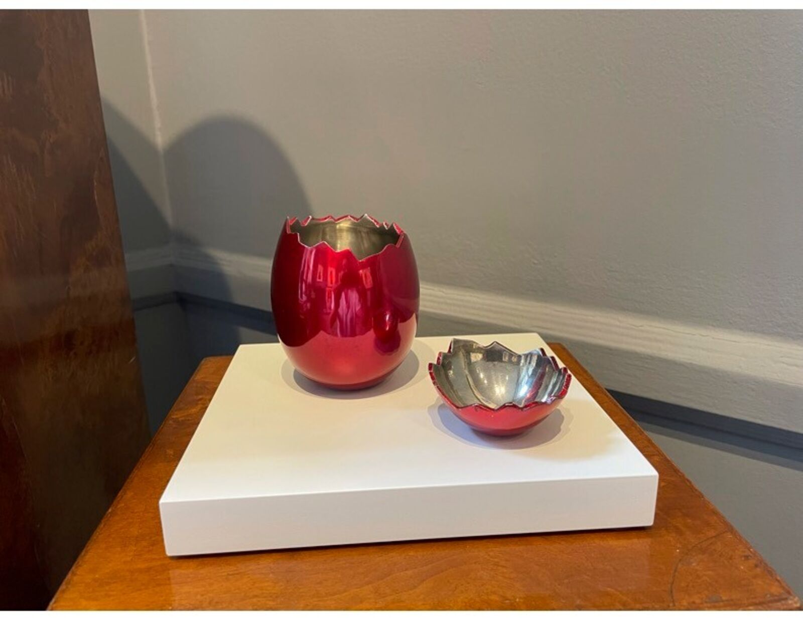 A red vase and a white bowl sitting next to each other.