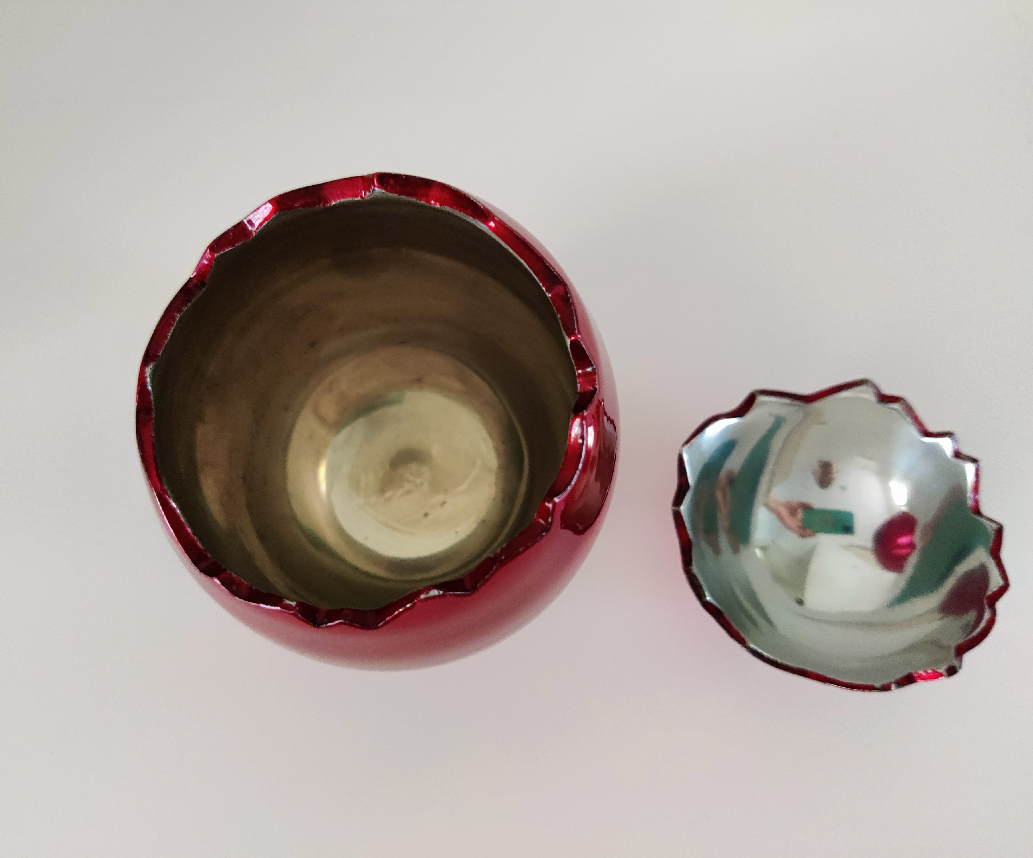 A red vase and a broken glass bowl on a white surface.