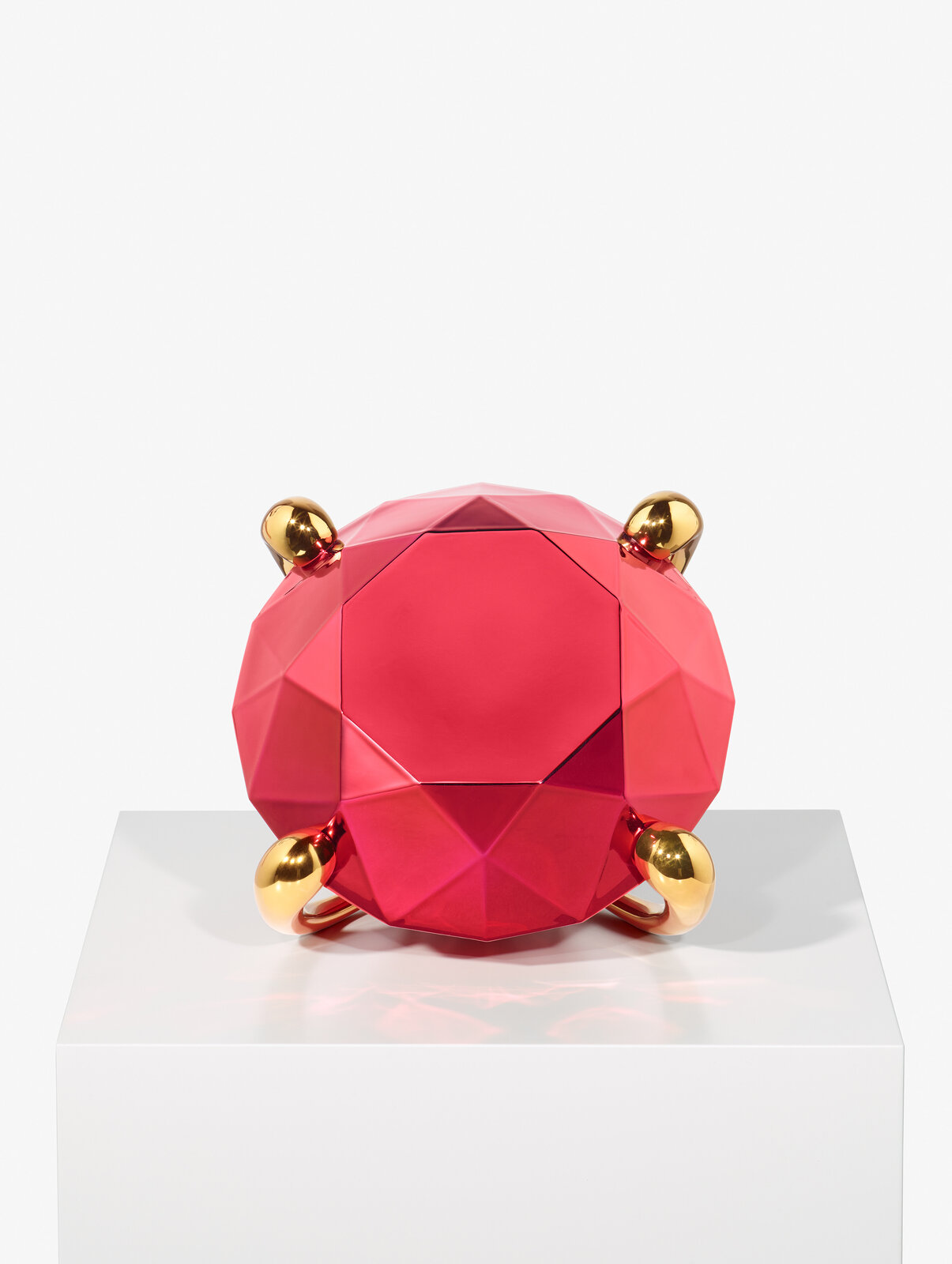 A geometric, faceted pink pitcher with gold handles and feet.