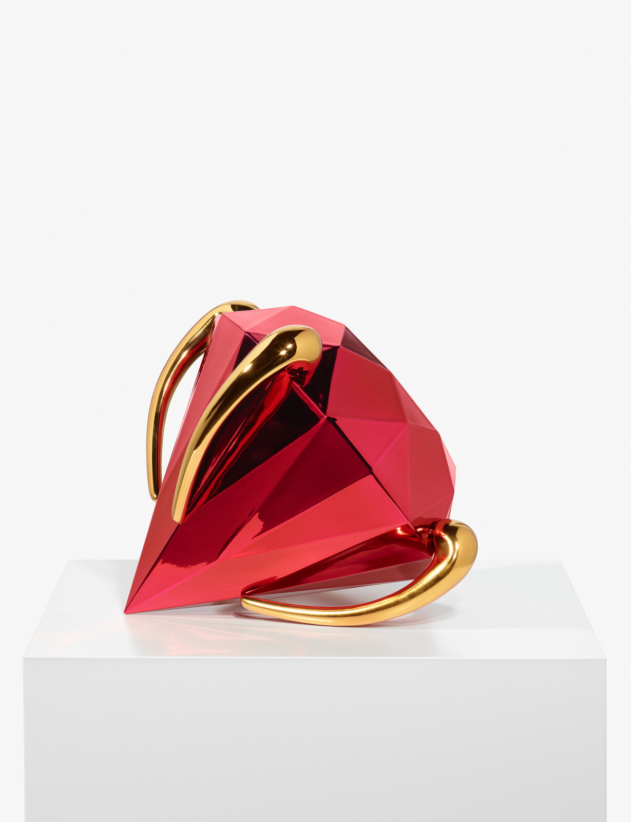 A geometric, faceted pink pitcher with gold handles and feet.