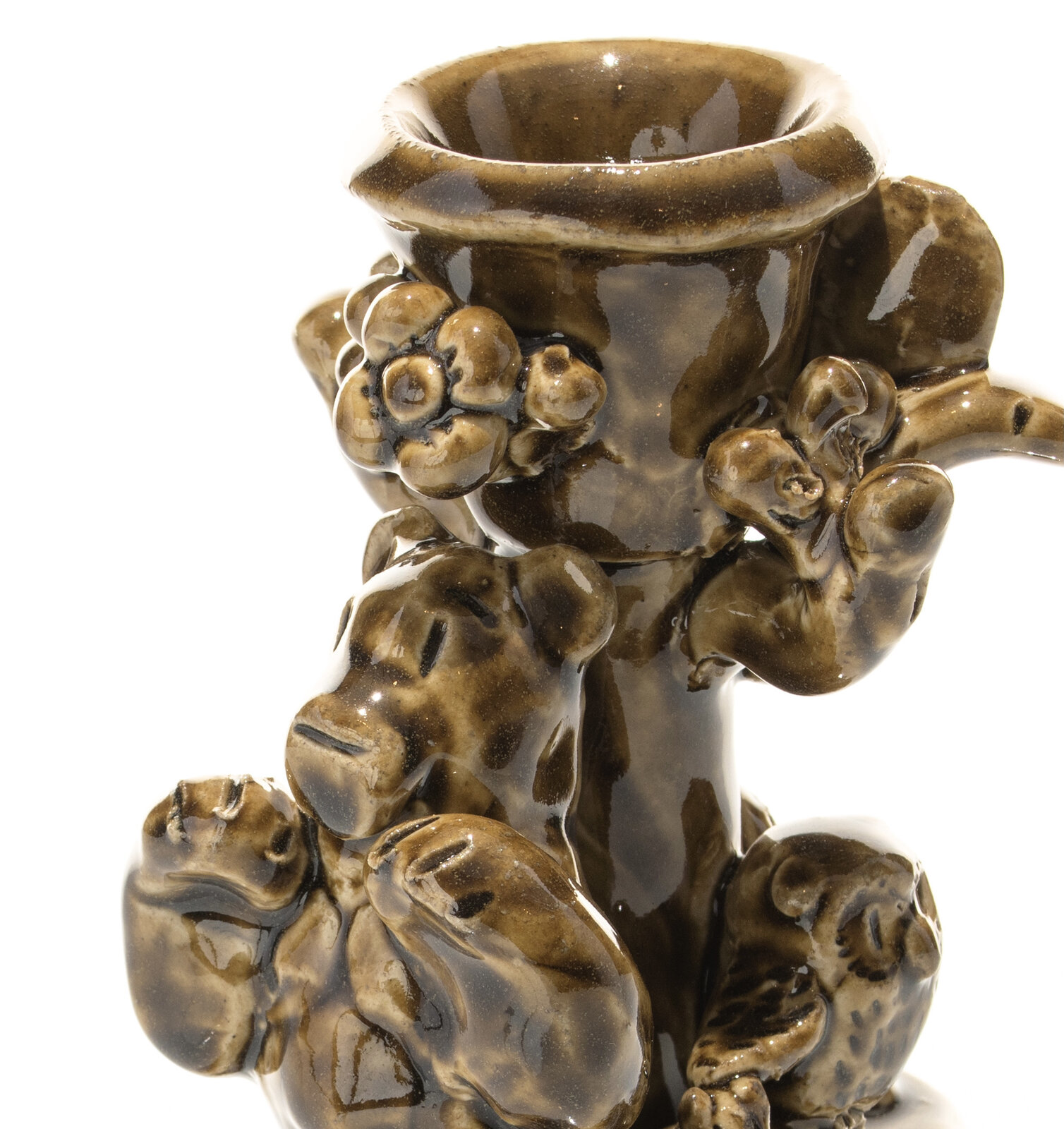 A glossy brown ceramic candlestick featuring a textured, organic design with animal-like figures and floral elements.