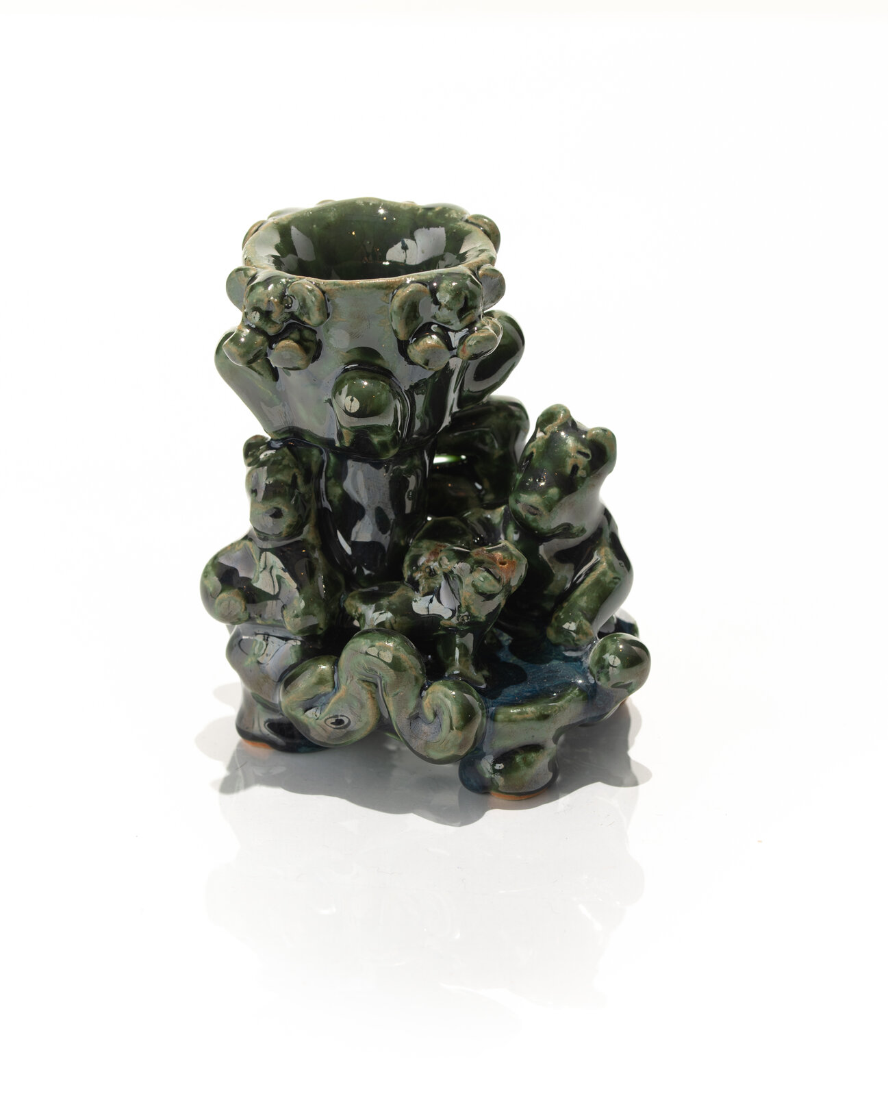 A glossy green ceramic sculpture featuring a central cup surrounded by small animal figures.