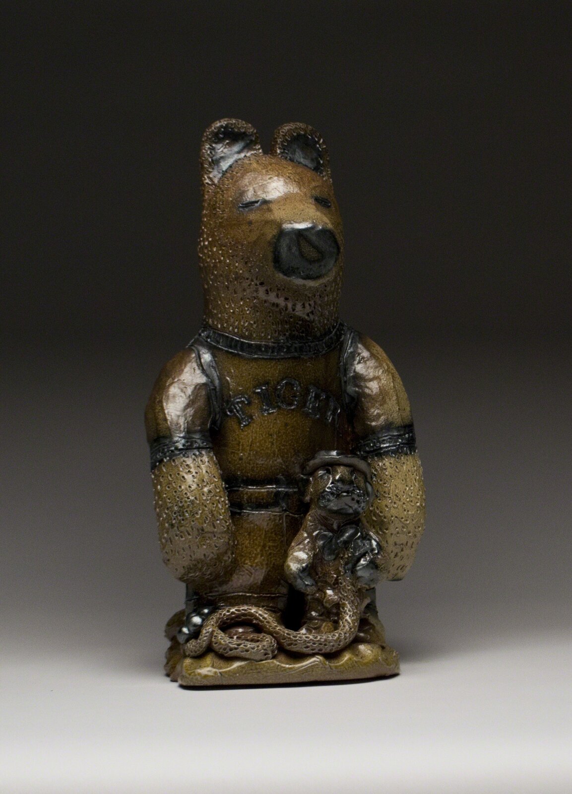A ceramic figurine of a bear-like figure in a wrestling outfit holding a small snake.