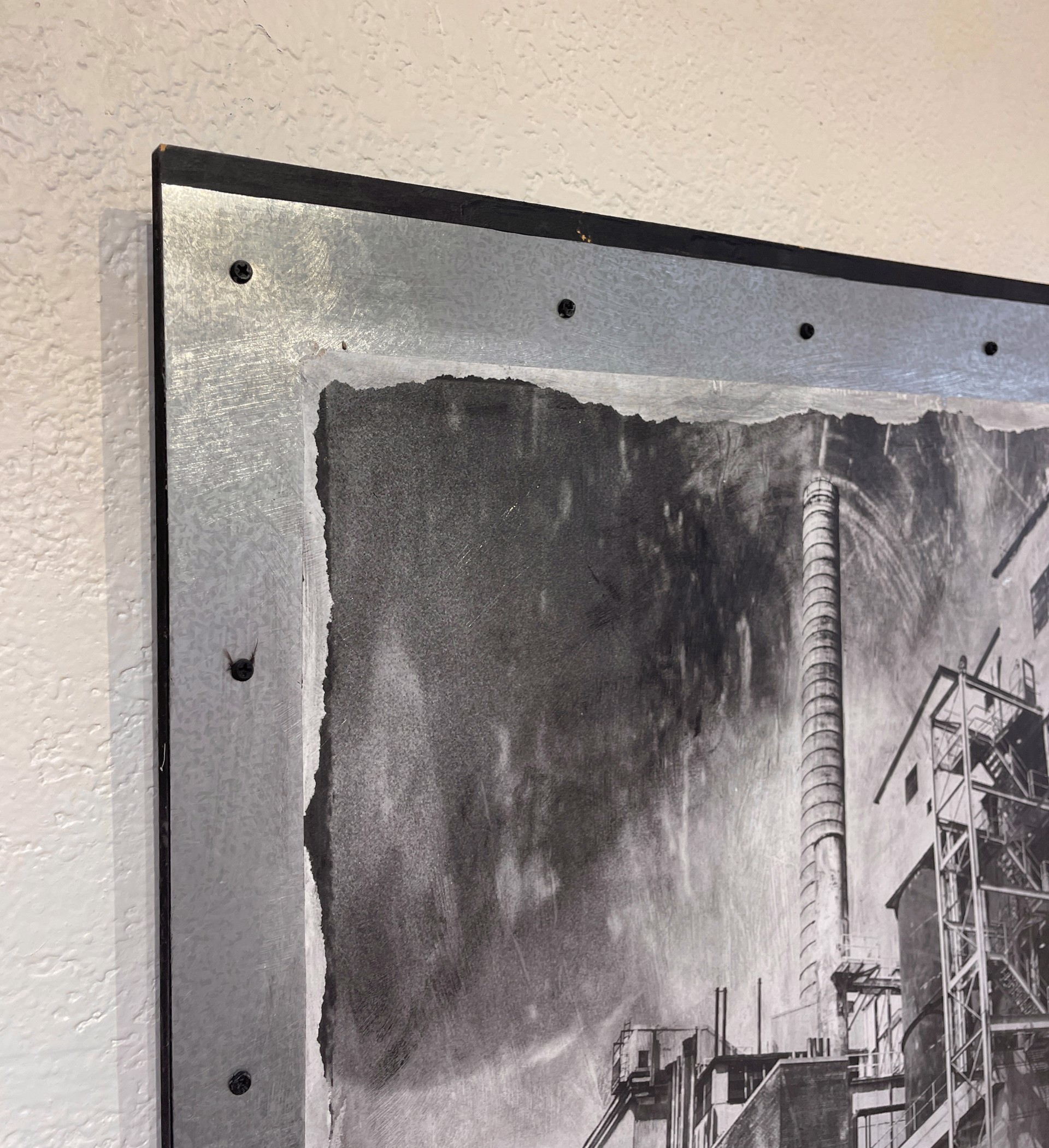 A black and white photo of a factory with smoke coming out of it.
