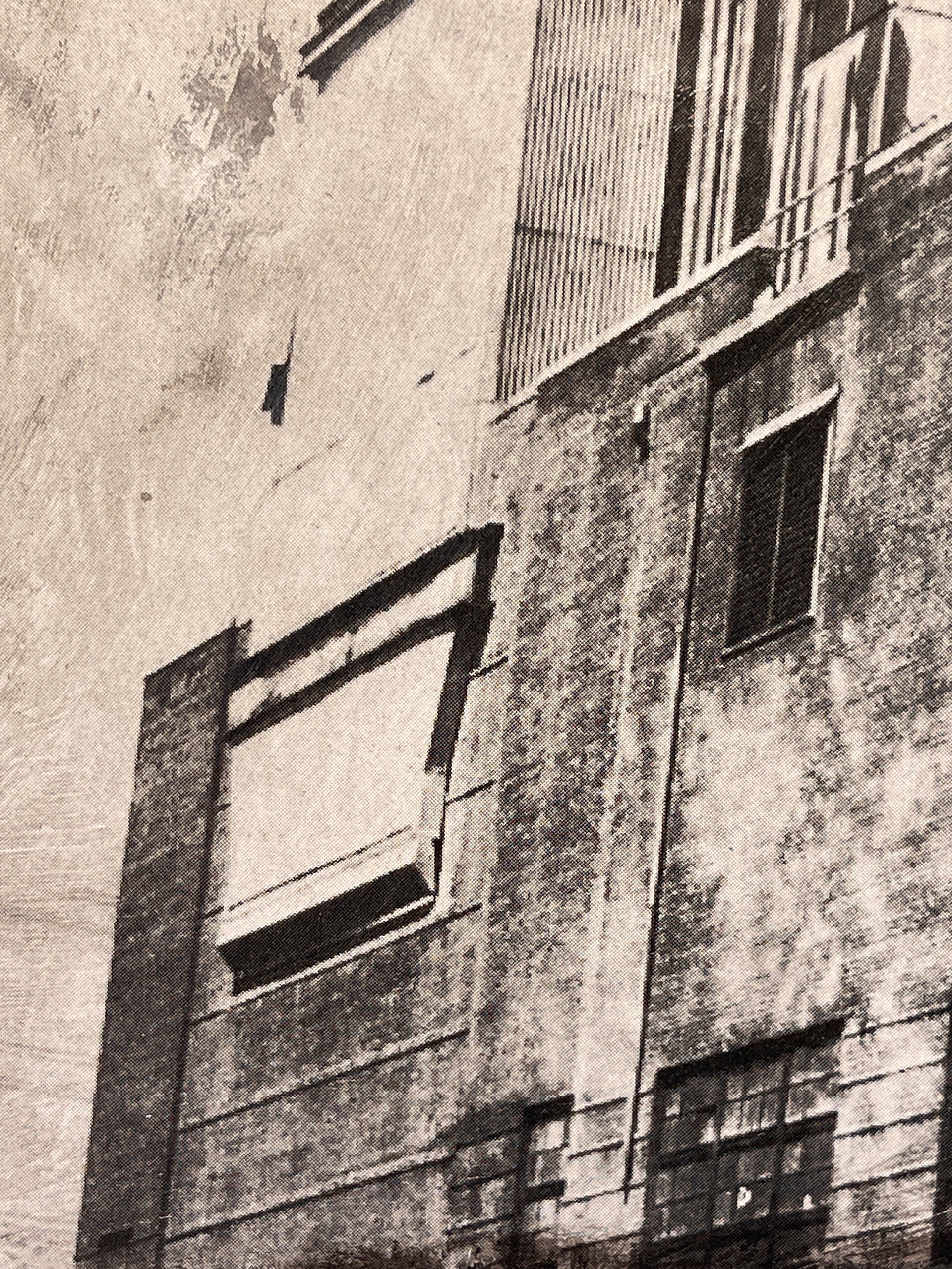 A black and white photo of a factory with smoke coming out of it.