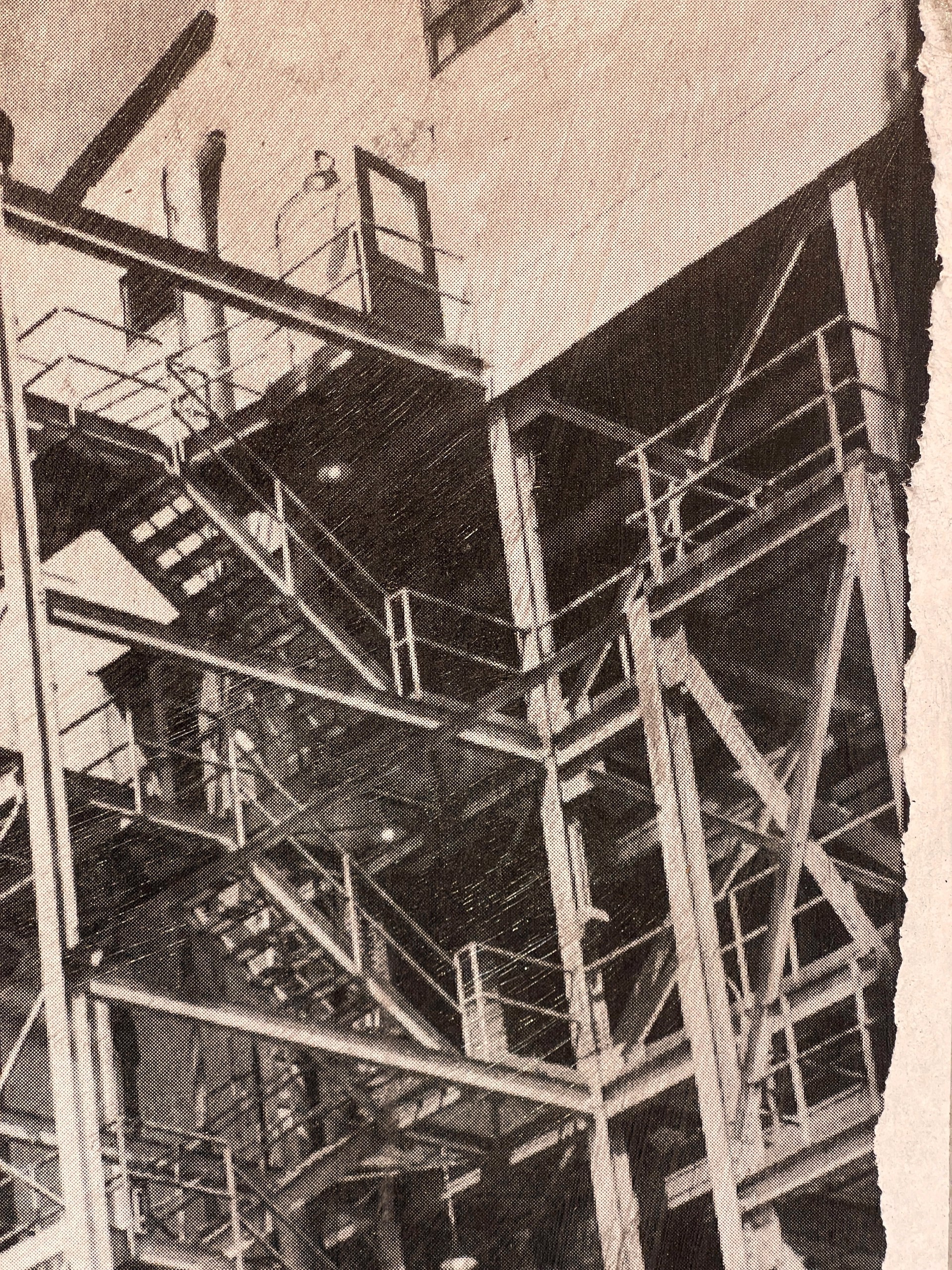 A black and white photo of a factory with smoke coming out of it.