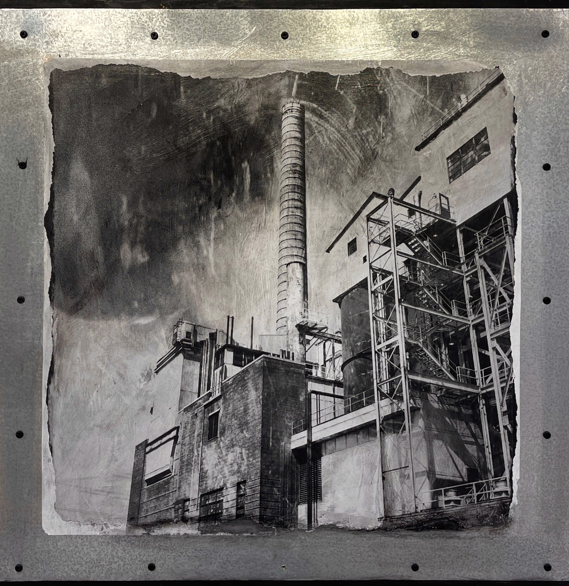 A black and white photo of a factory with smoke coming out of it.