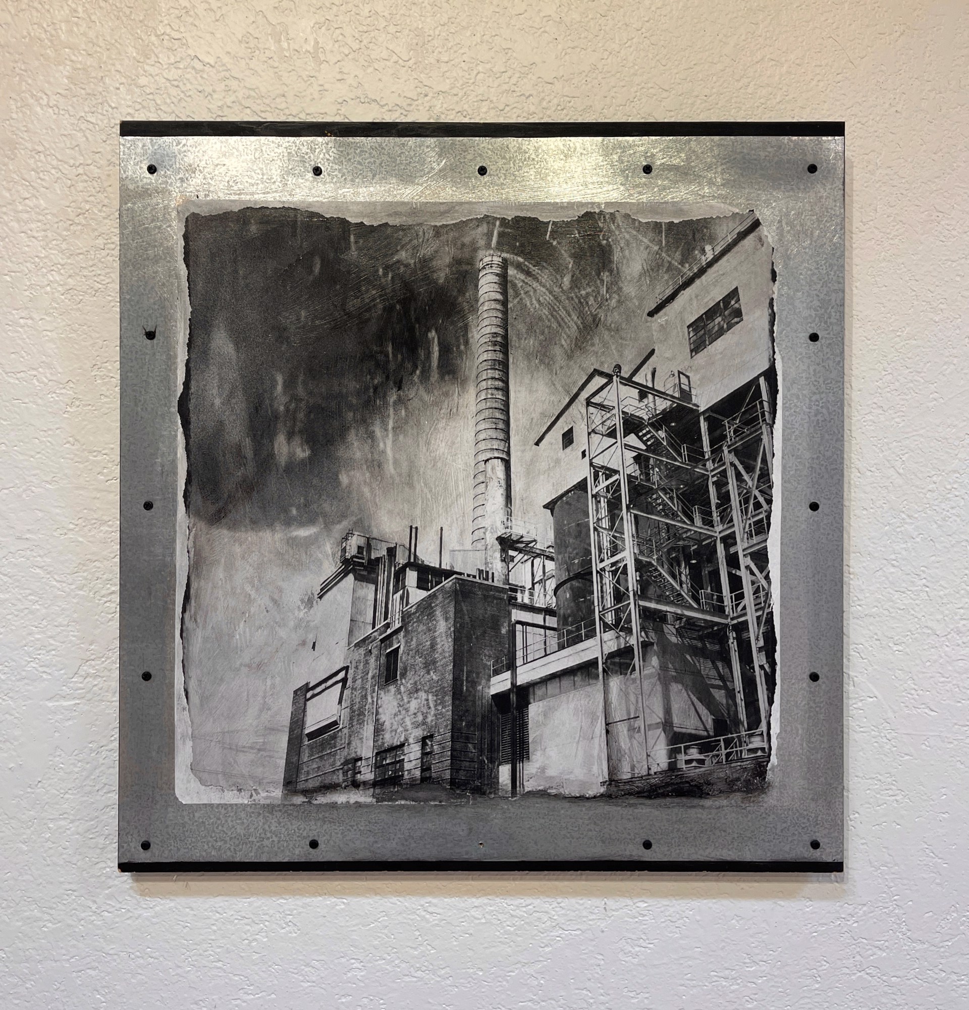 A black and white photo of a factory with smoke coming out of it.