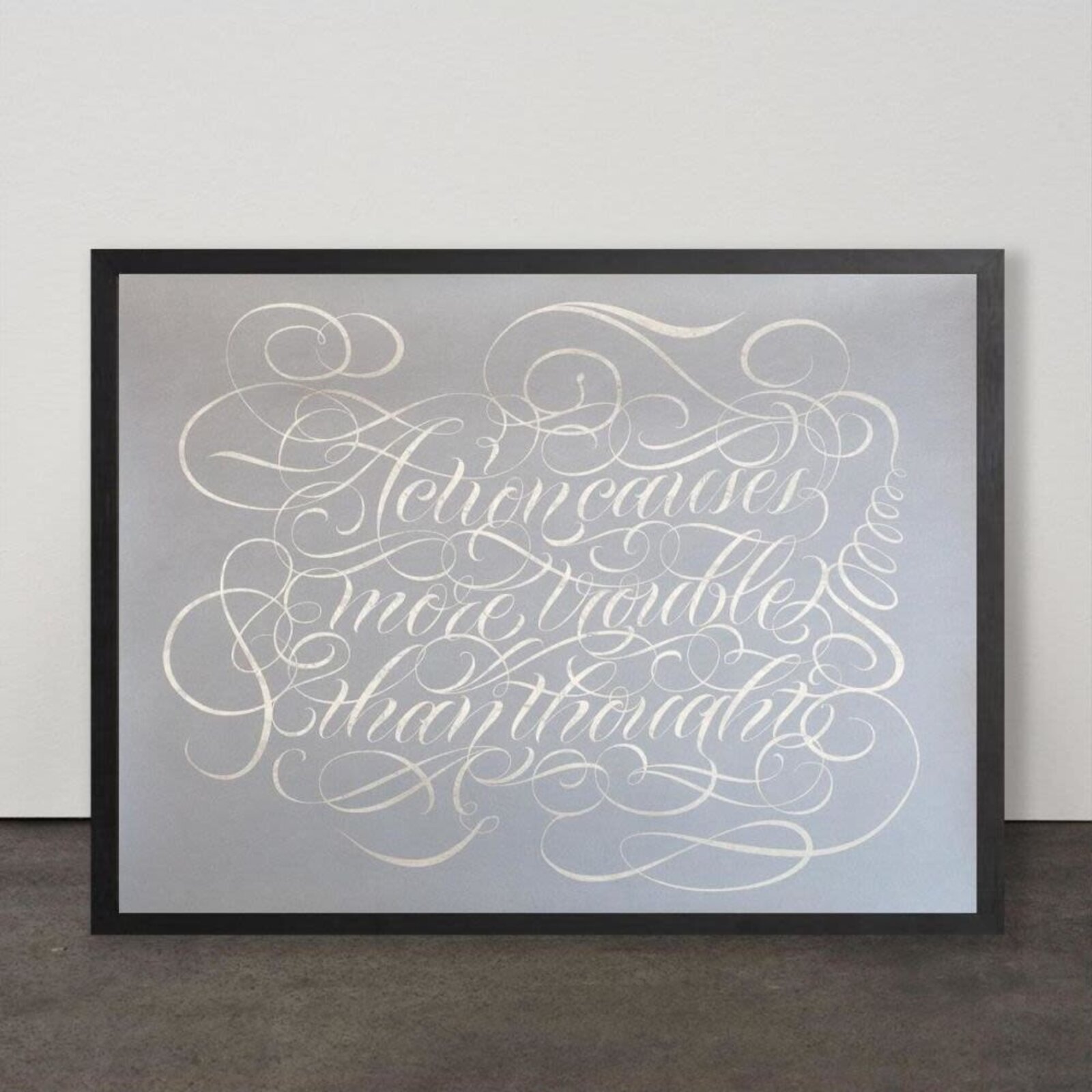 A silver metallic print of ornate calligraphy on a matte grey background.