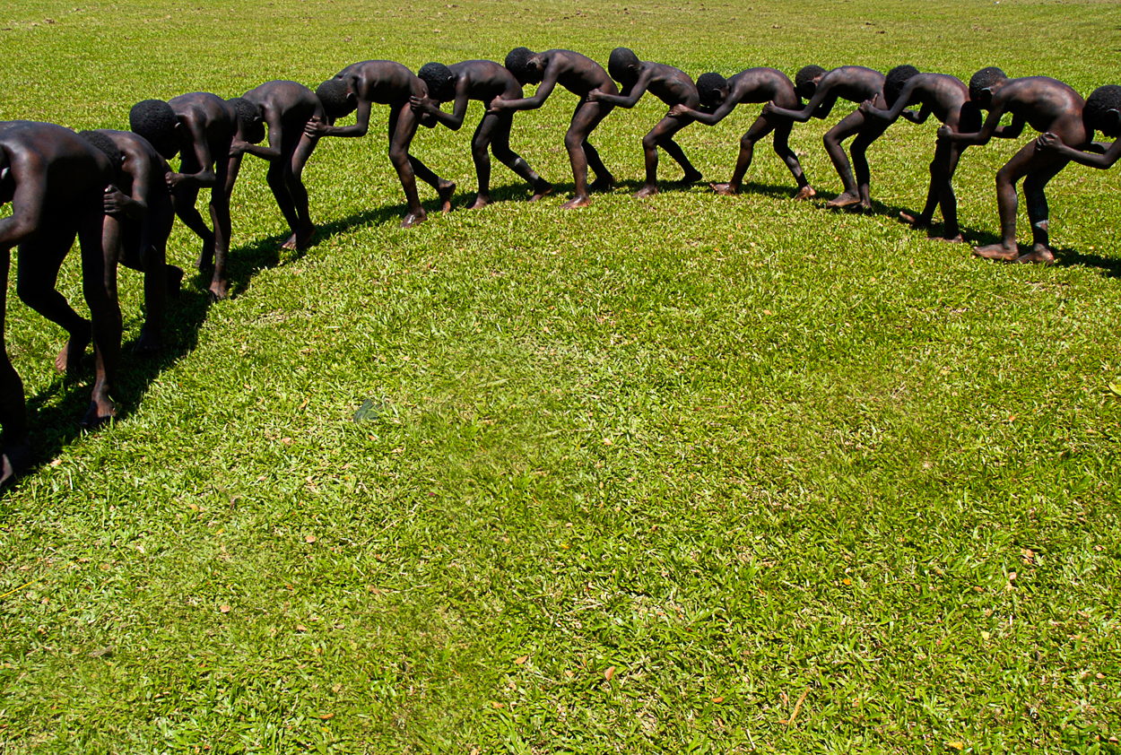 A group of black men standing in a circle on a grassy field.