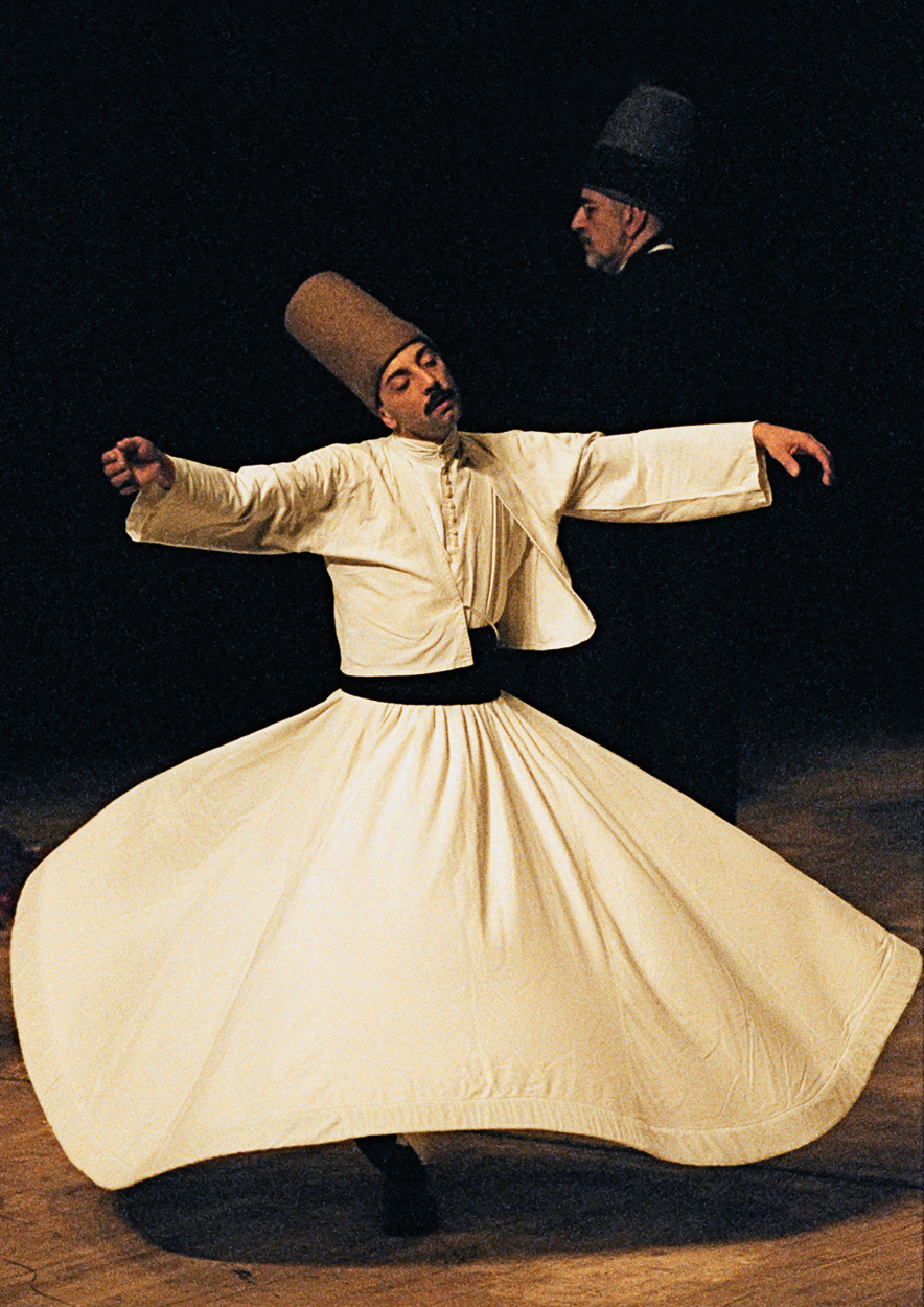 A man in a white dress and a man in black hat dancing.