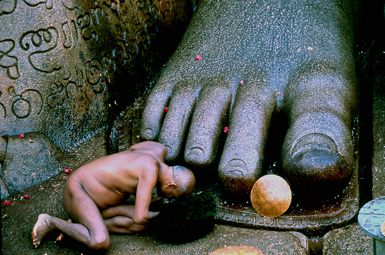 A small child kneeling down next to a large statue.