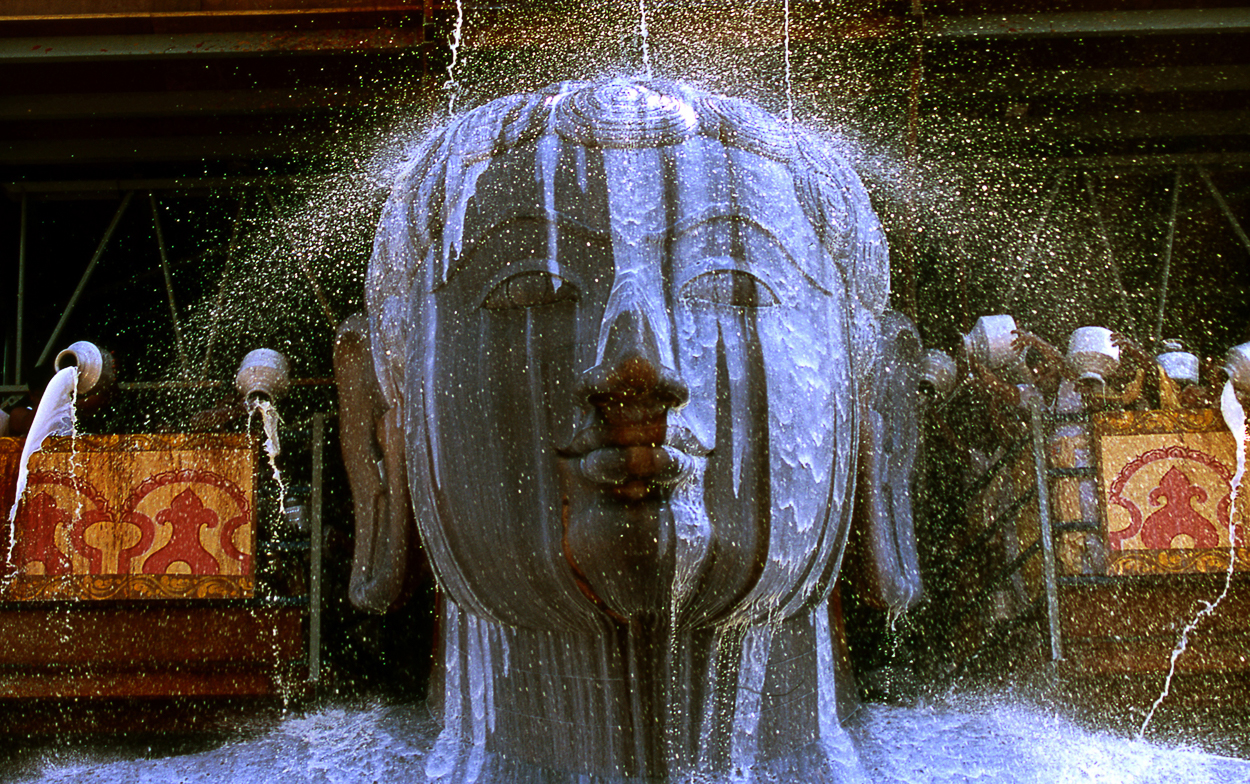 A statue of a buddha head in the middle of a fountain.