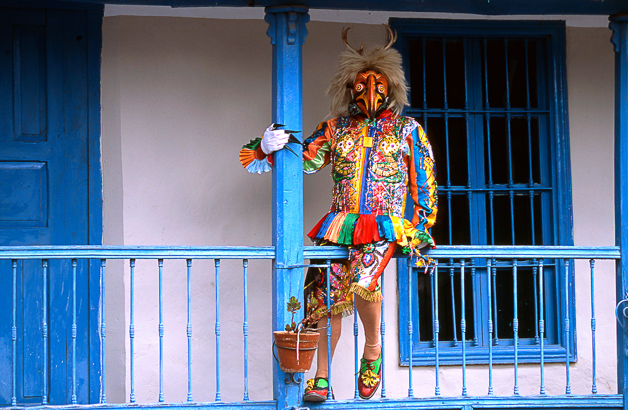 A woman in a colorful costume standing on a balcony.