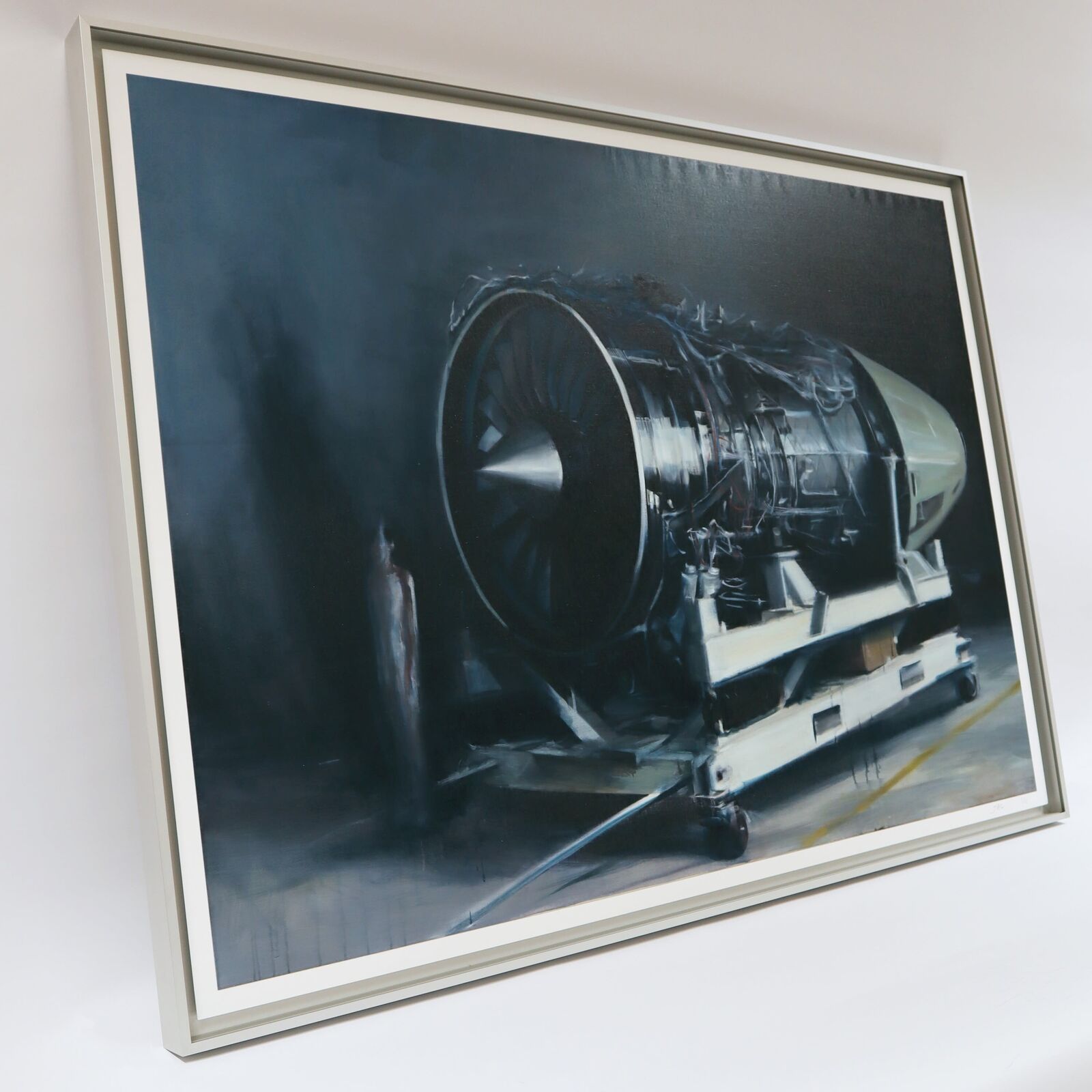 A painting of a jet engine on a cart in a hangar.