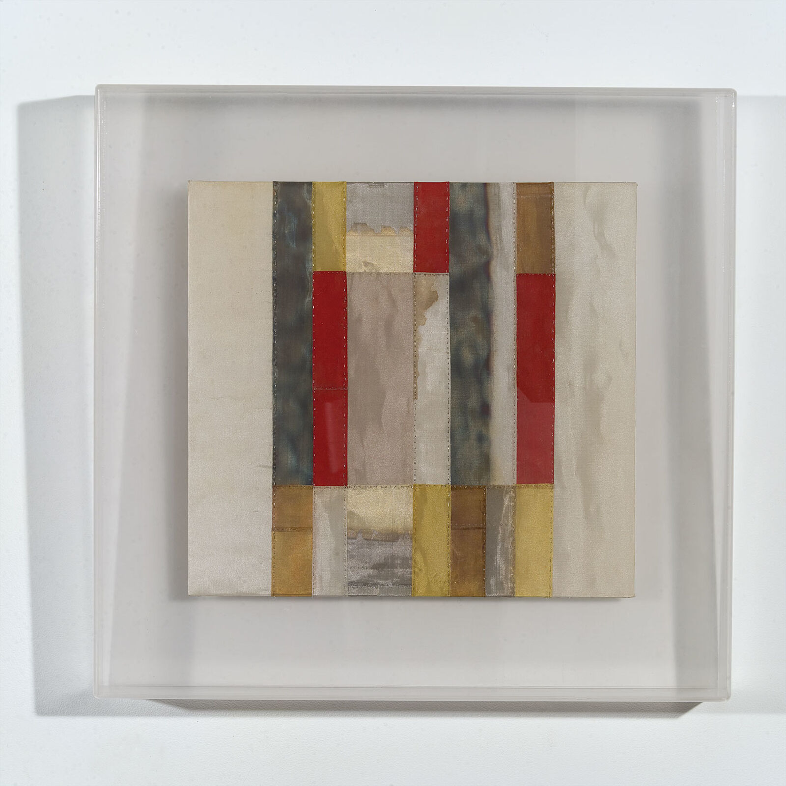 A minimalist abstract composition featuring vertical fabric strips in muted earth tones and reds.