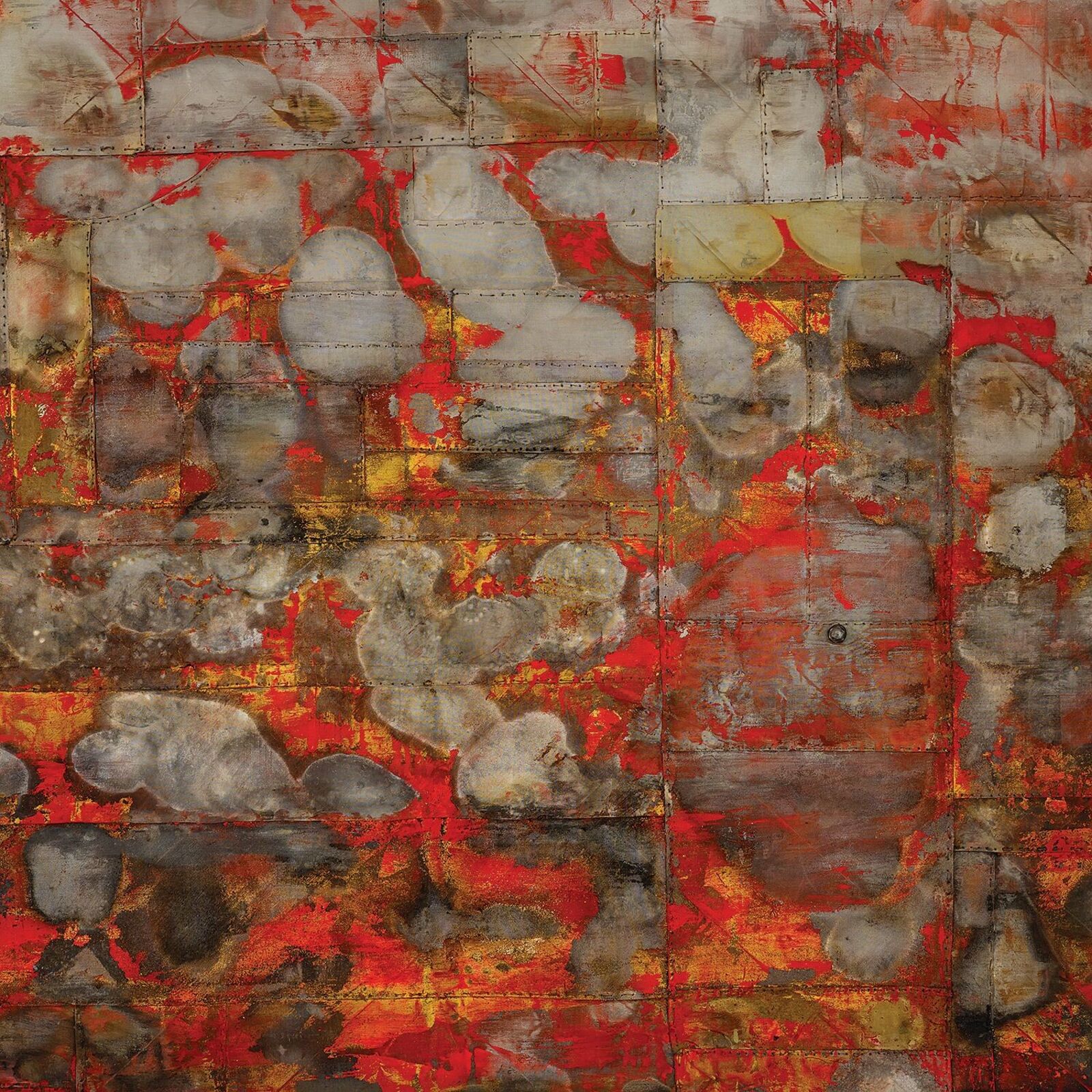 A textured abstract painting with red and gold tones hangs on a white wall in an industrial-style room.