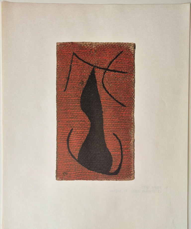 A black cat sitting on top of a red and black tile.