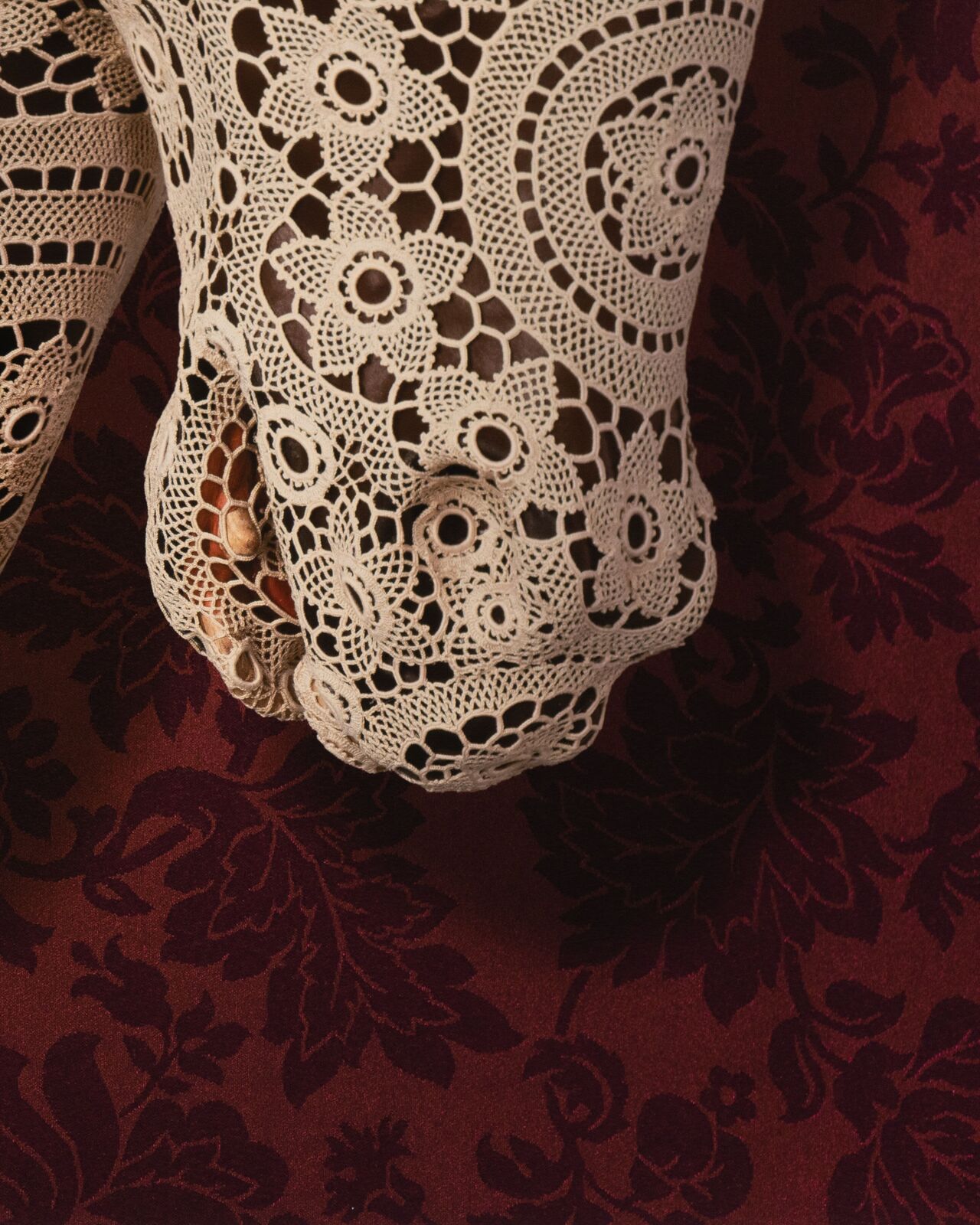 A white lace horse head mounted on a dark floral background.