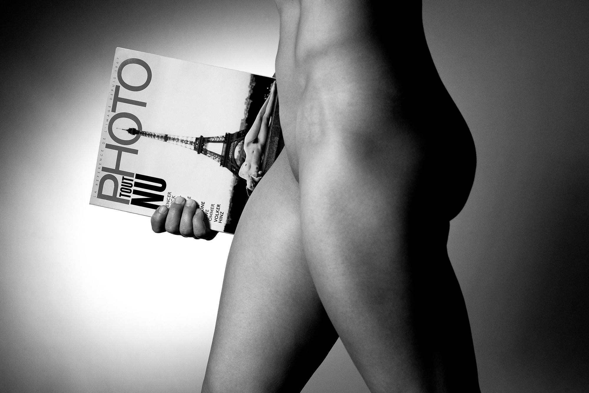 A woman holding a magazine with a picture of the Eiffel Tower in the background.