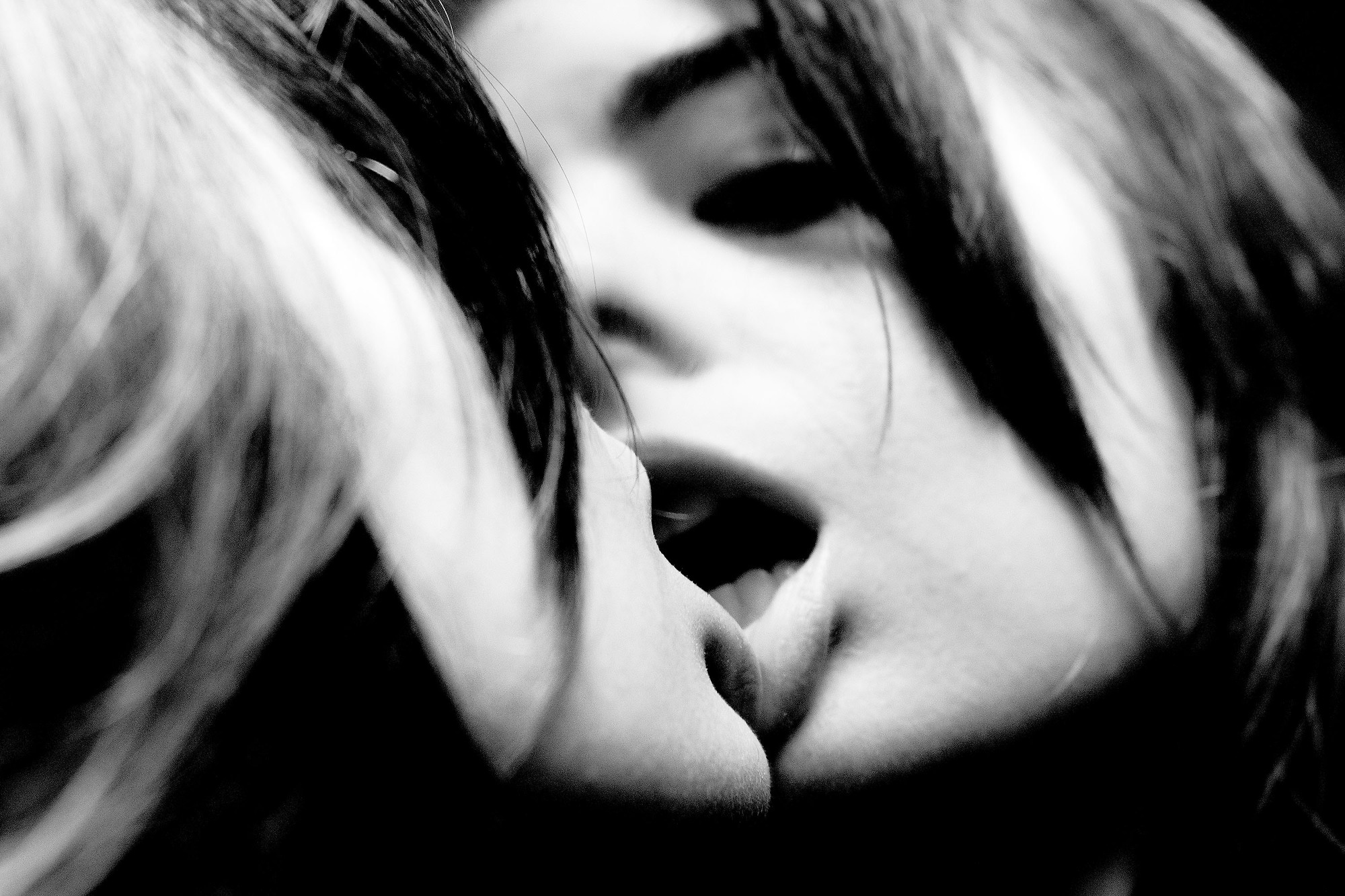 A black and white photo of a woman kissing another woman.
