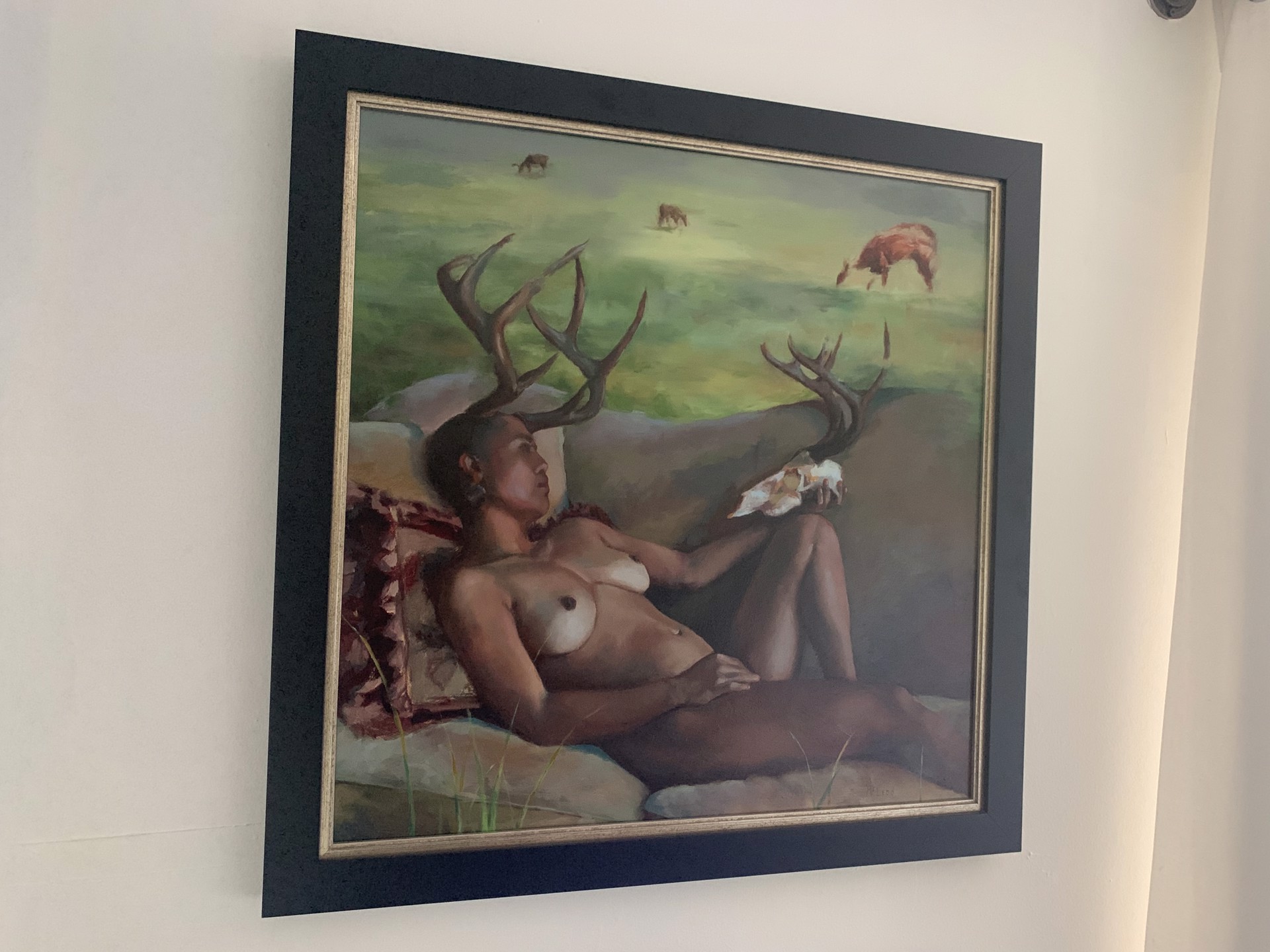 A reclining figure with antlers and a skull, set against a pastoral landscape.