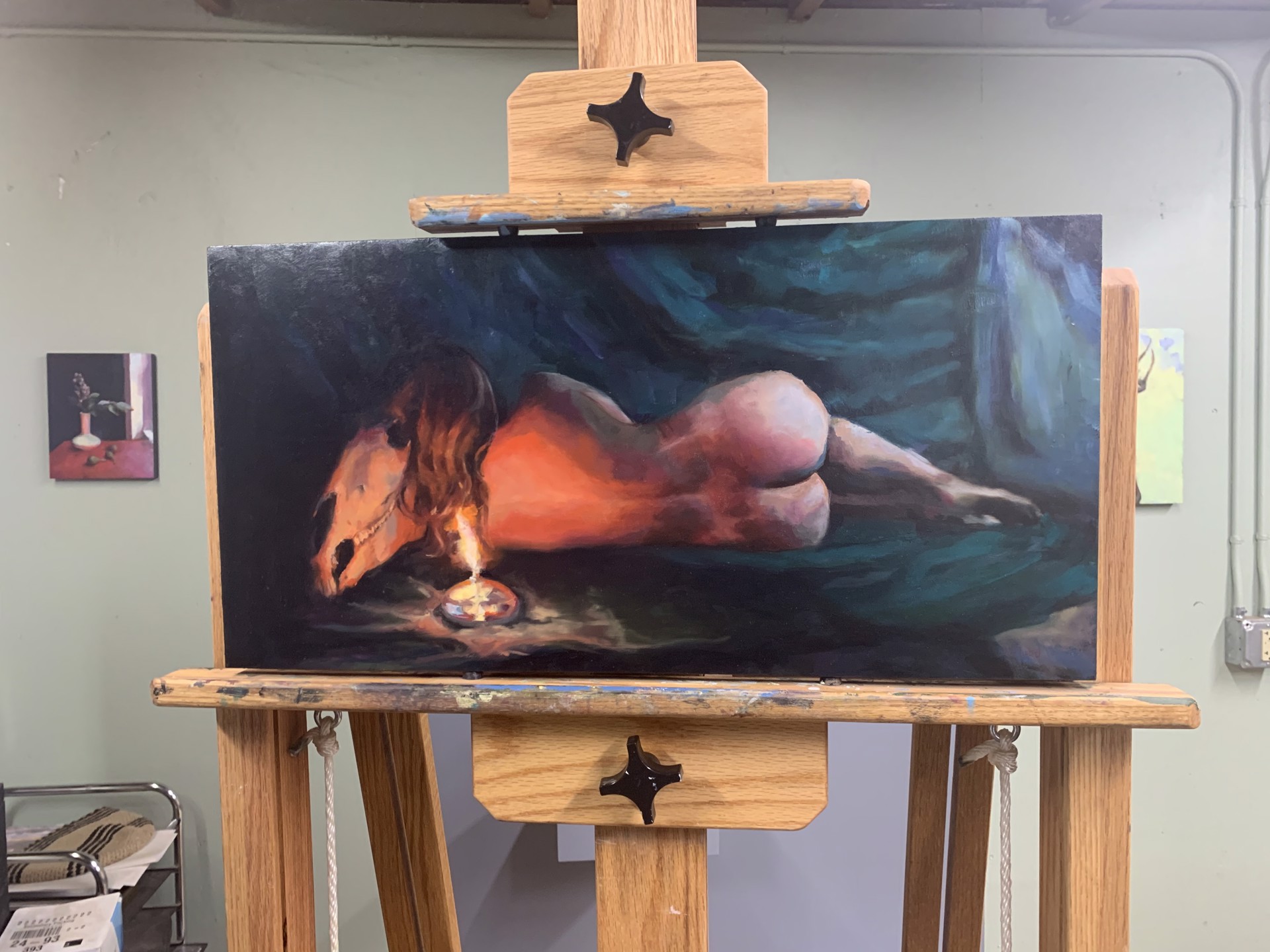 A painting of a woman laying on a bed next to a candle.