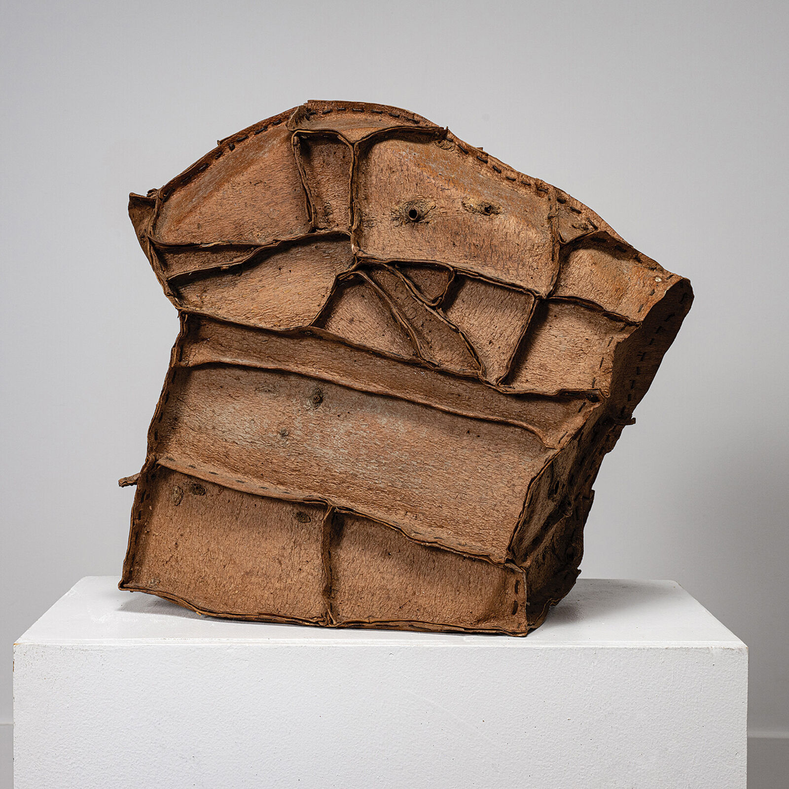 A sculptural piece resembling a cracked, layered rock resting on a white pedestal.