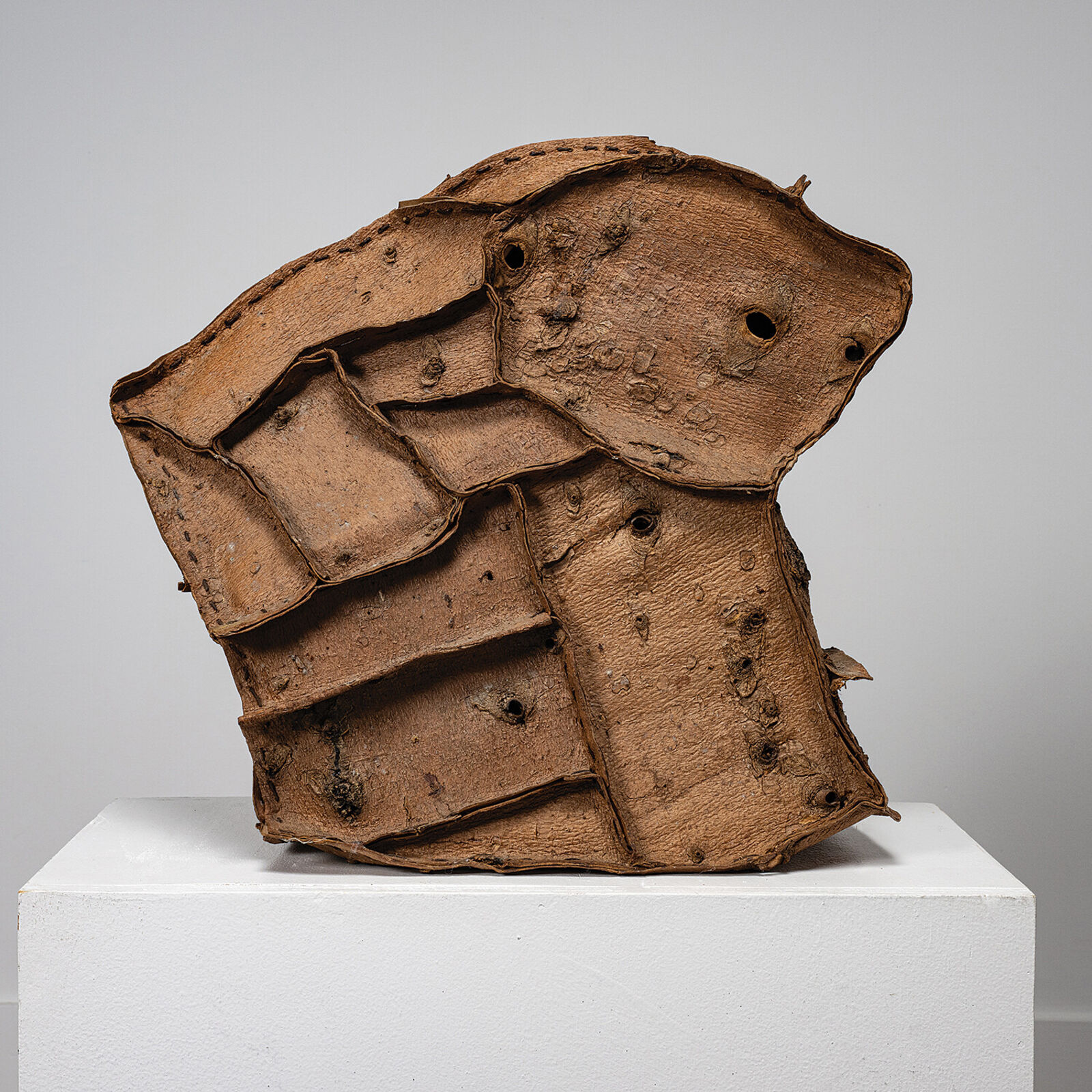 A sculptural piece resembling a cracked, layered rock resting on a white pedestal.