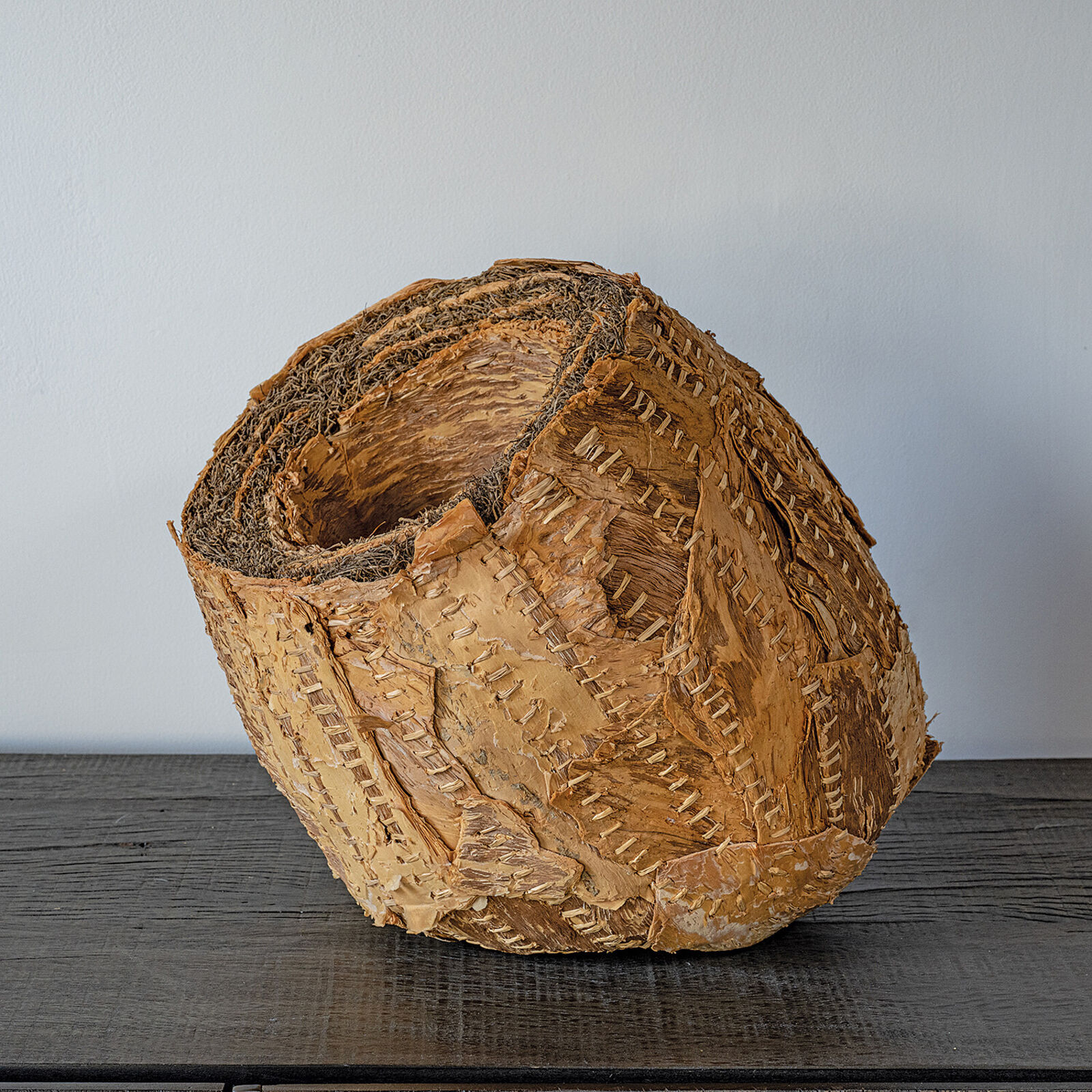 A sculptural sphere made of layered, stitched natural materials.