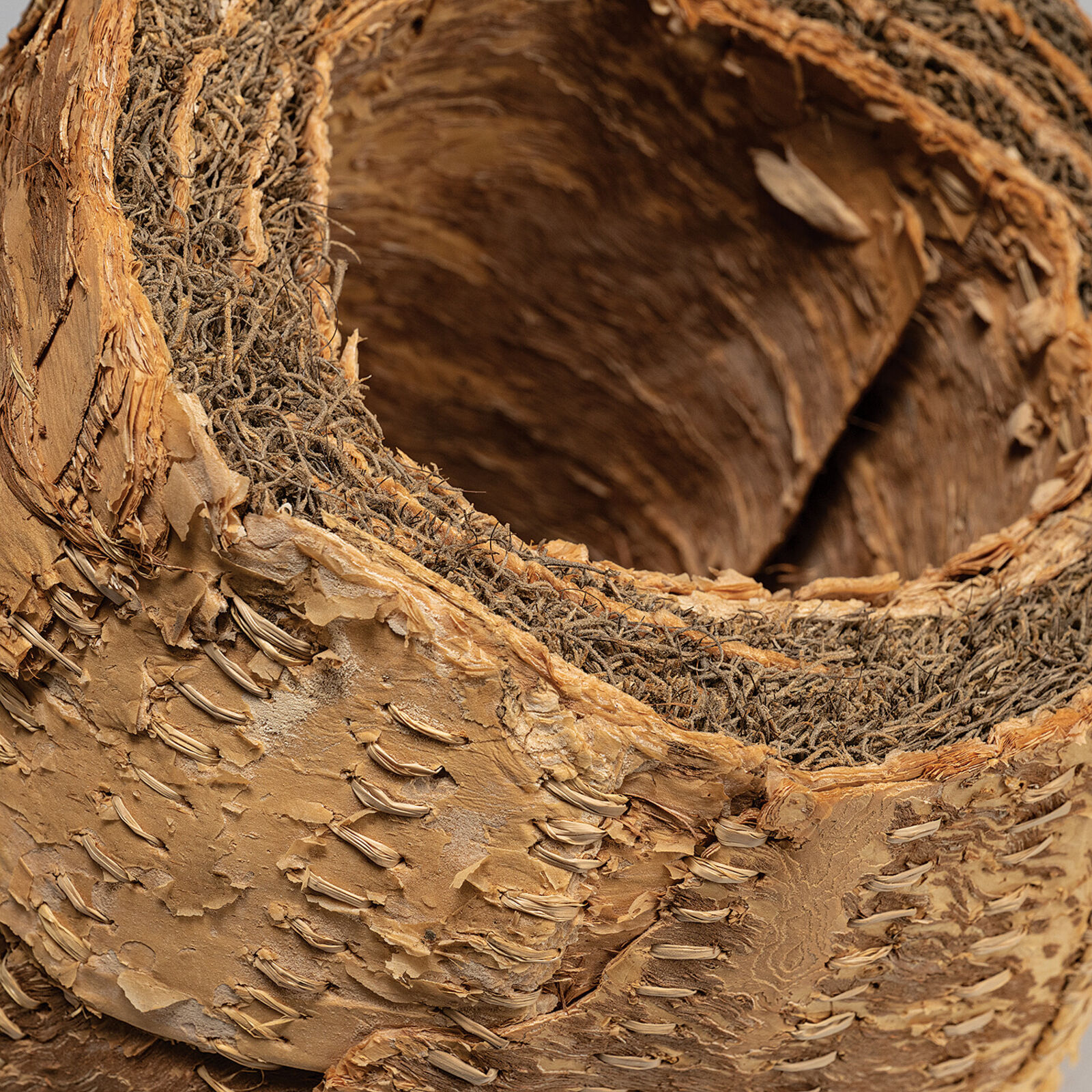 A sculptural sphere made of layered, stitched natural materials.