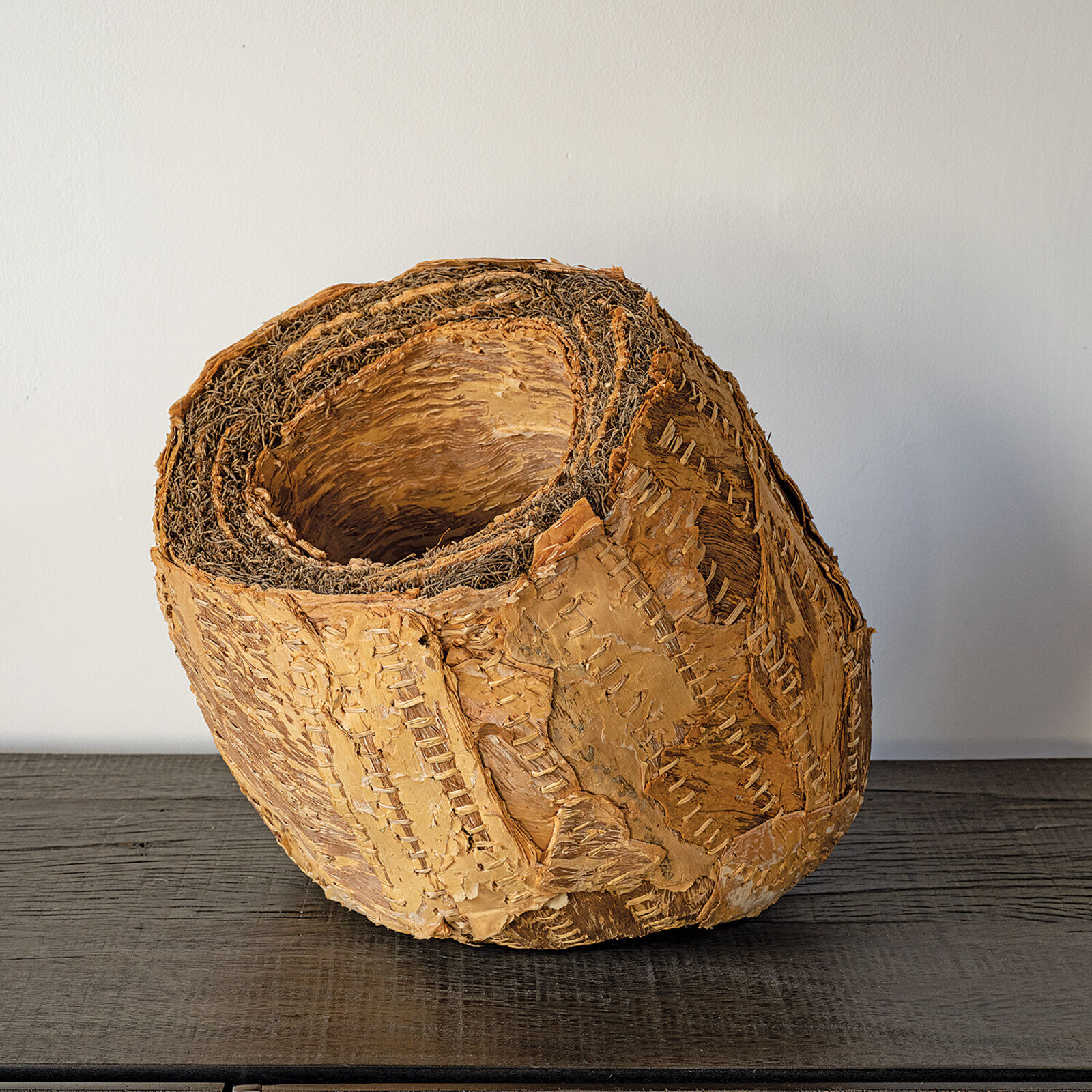 A sculptural sphere made of layered, stitched natural materials.
