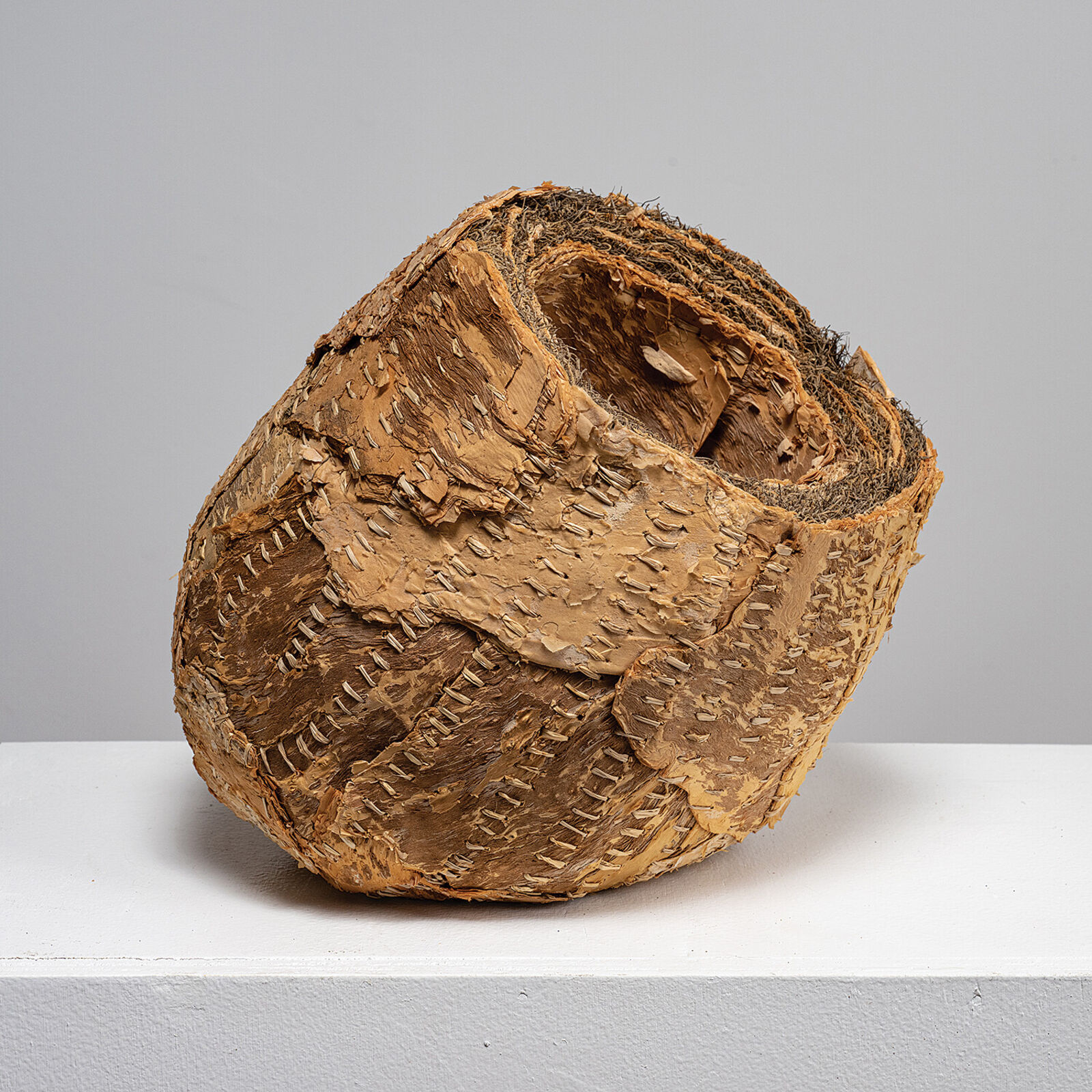 A sculptural sphere made of layered, stitched natural materials.