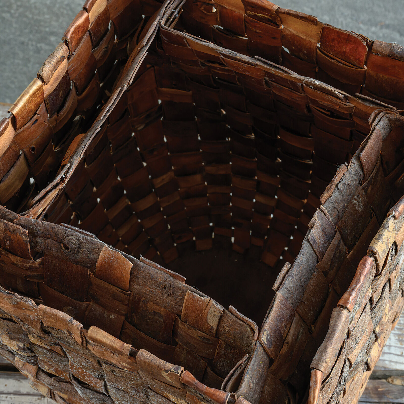 A woven basket sits on a weathered wooden plank against a slate background.