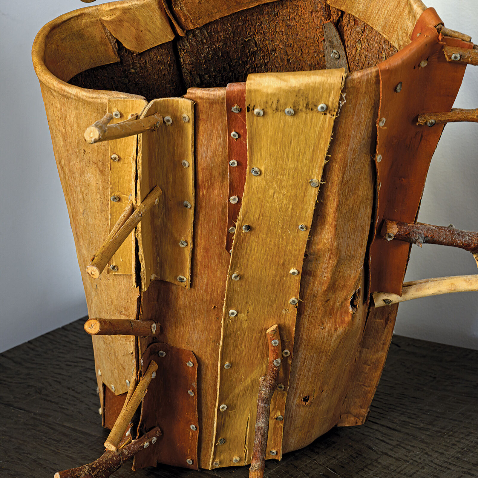 A rustic wooden sculpture resembling a stylized horn or branch, adorned with numerous small twigs.