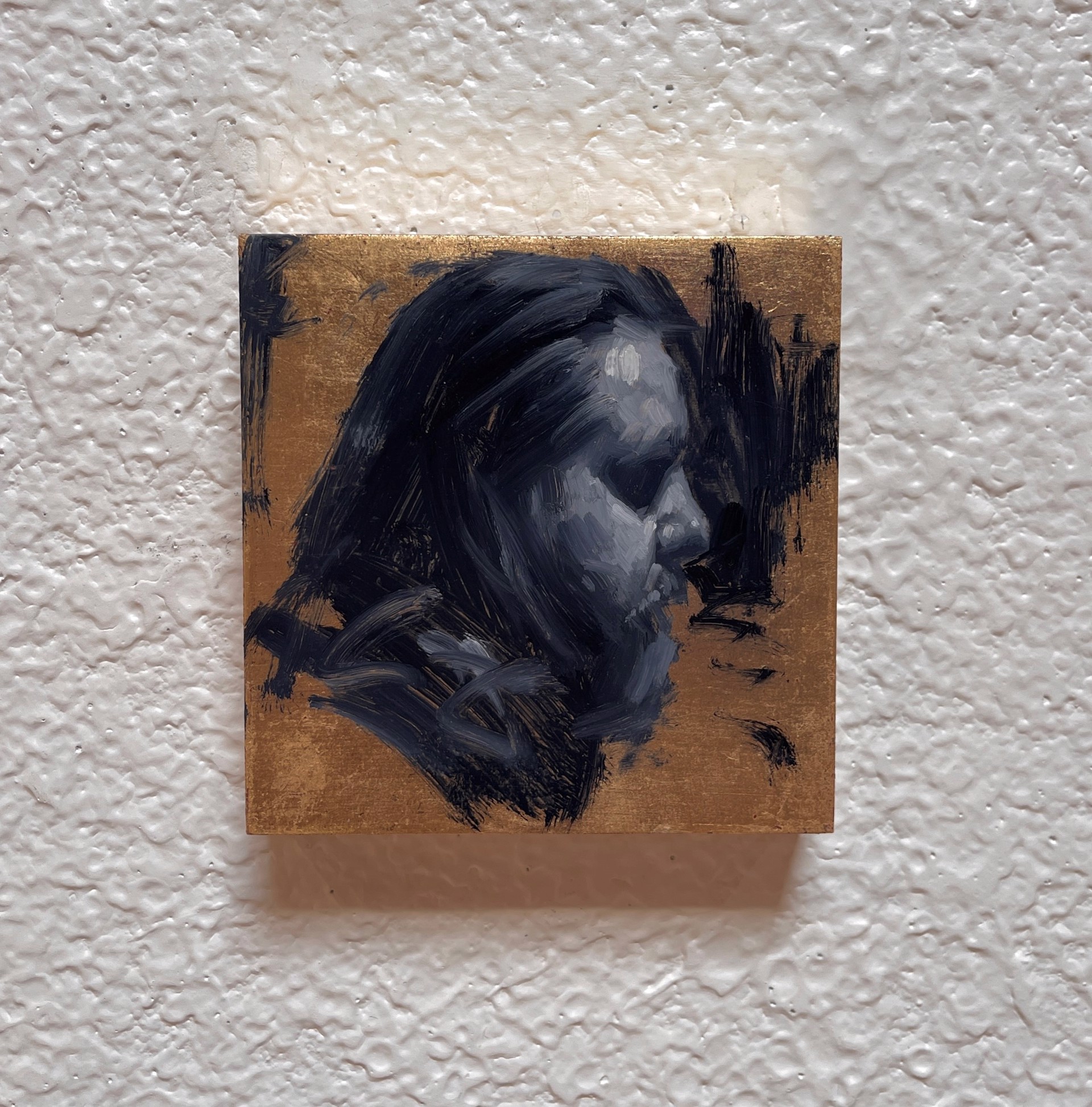 A painting of a man's face on a gold background.