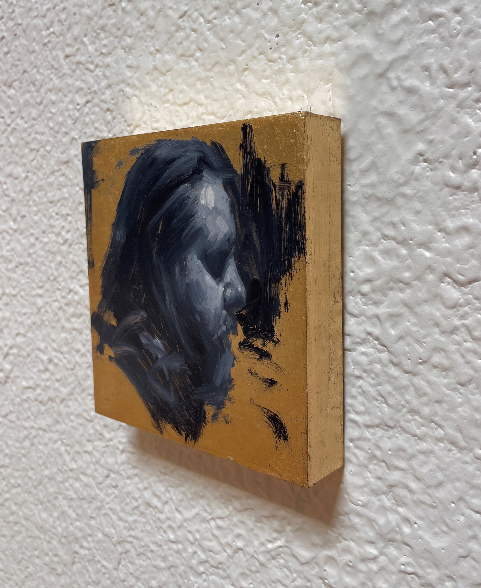 A painting of a man's face on a gold background.