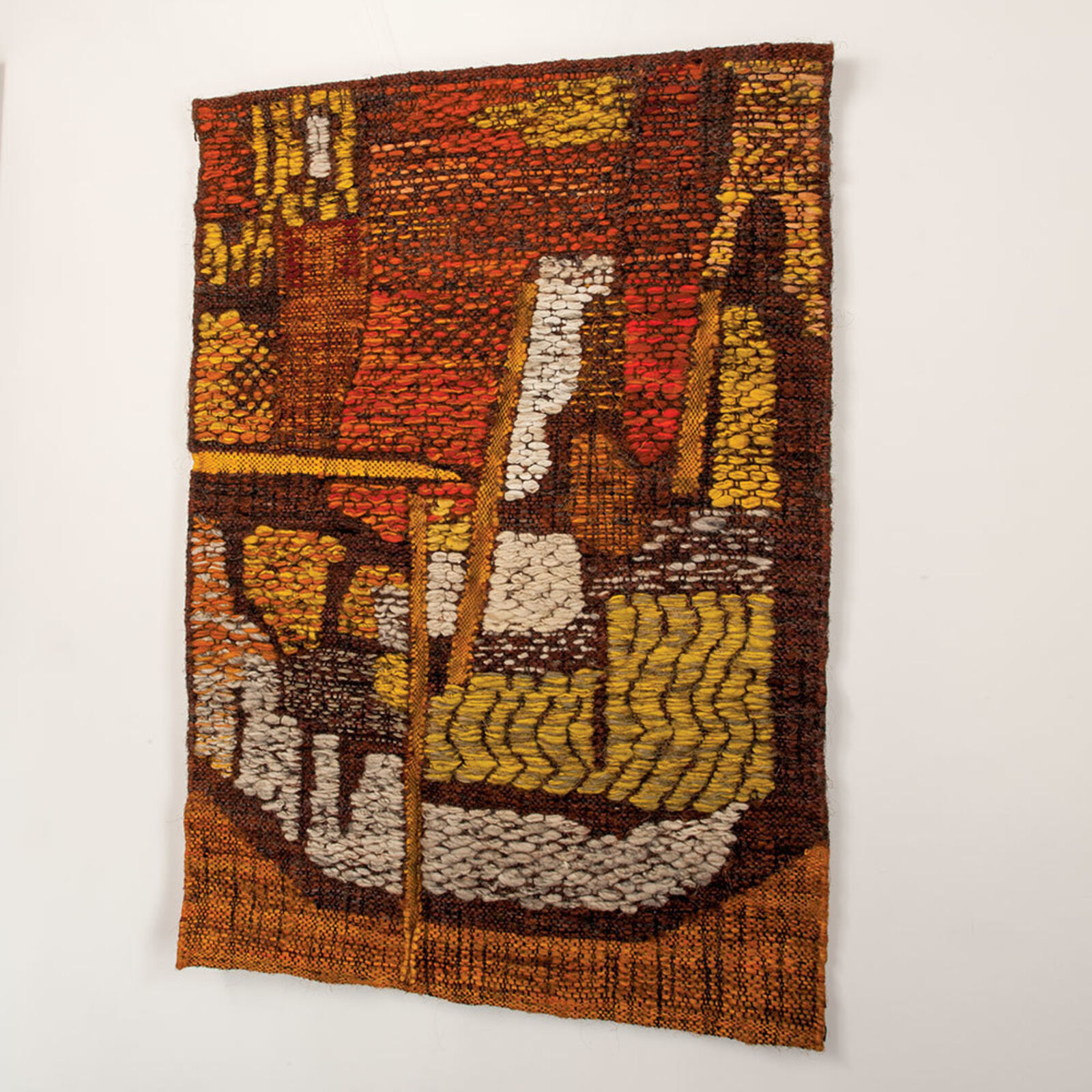 A woven textile artwork depicting a stylized landscape with warm earth tones and textured patterns.