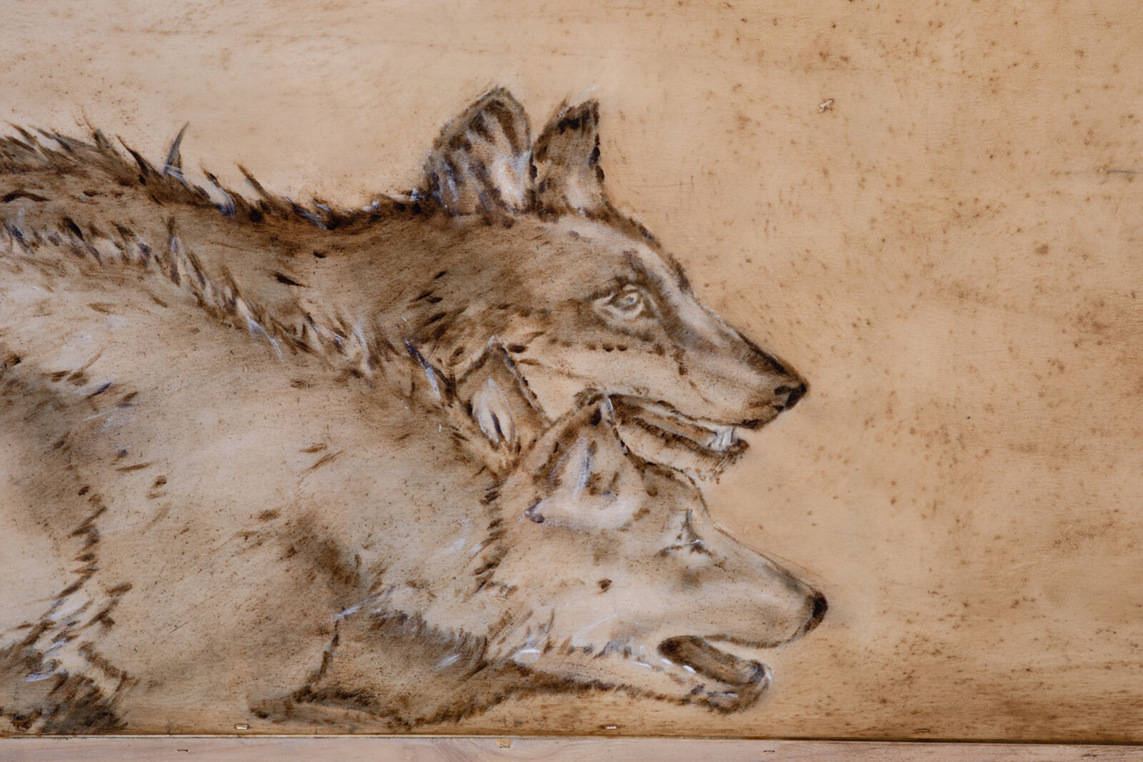 A woodburning artwork featuring a large bull and two wolves on a raw plywood surface.
