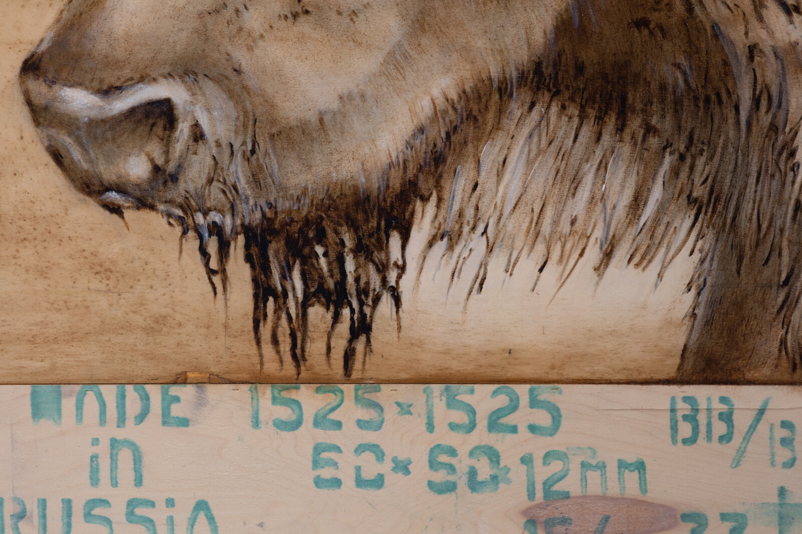 A woodburning artwork featuring a large bull and two wolves on a raw plywood surface.