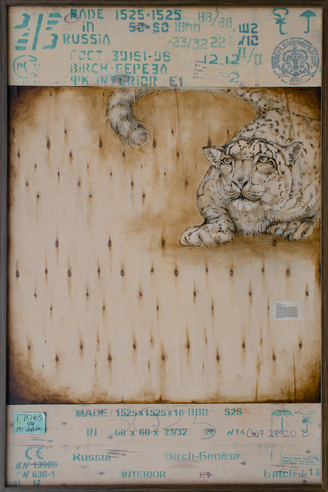 A realistic leopard resting on a weathered wooden surface, framed by industrial markings.