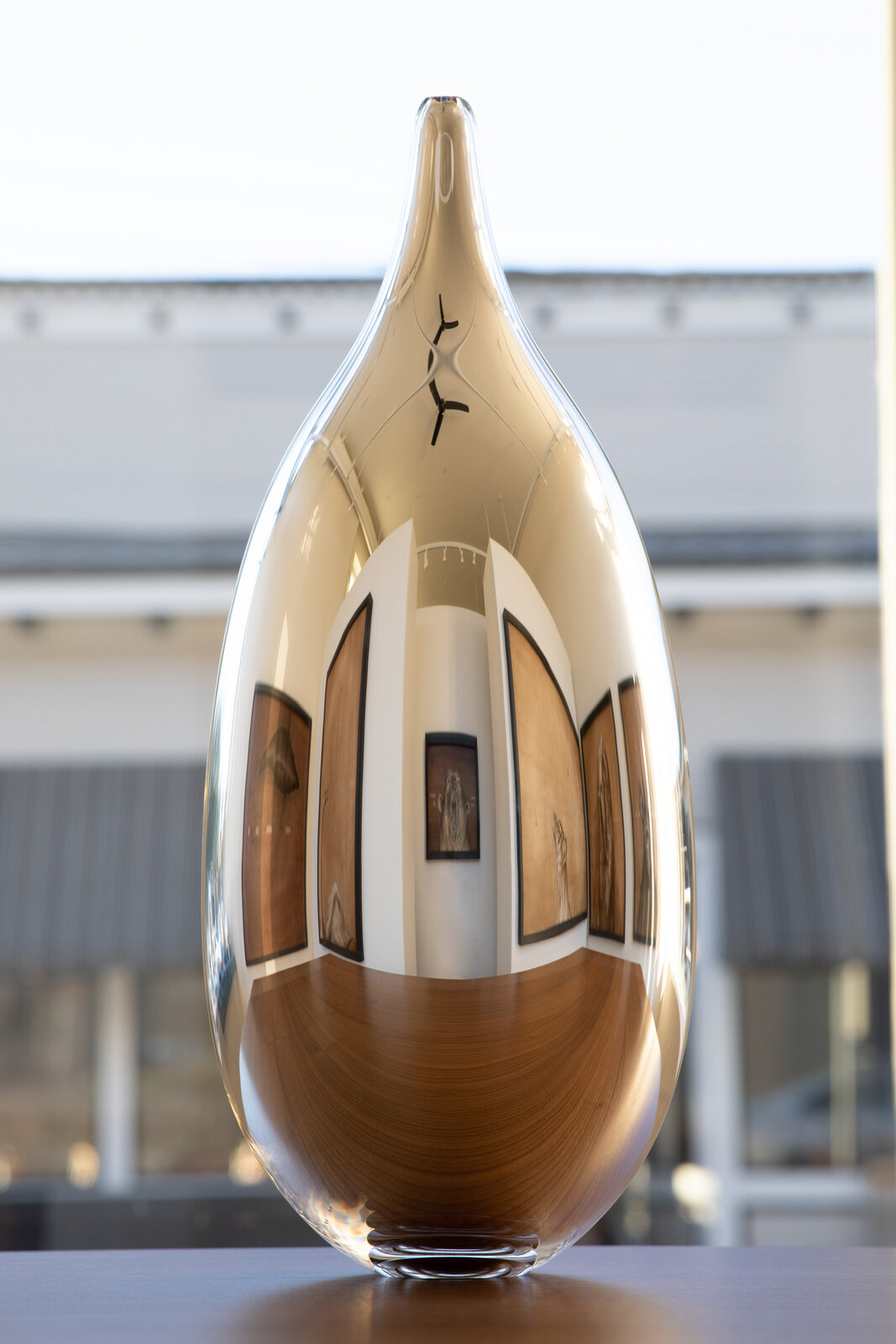 A reflective golden vase displaying a gallery interior.