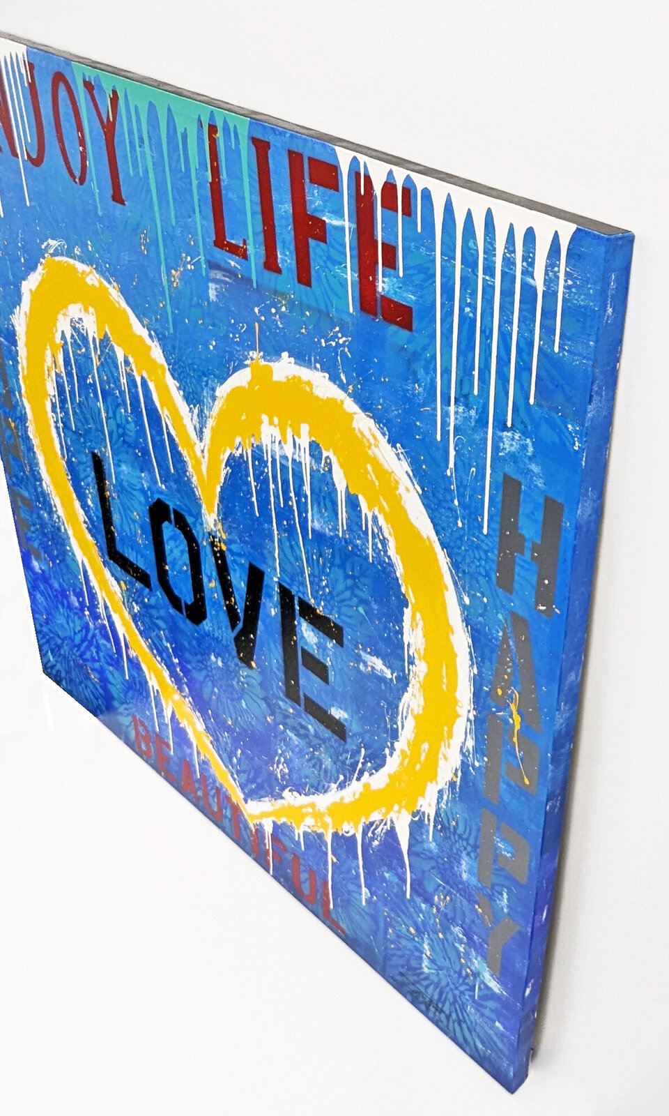 A painting of a yellow heart with the words enjoy life, love, happy, beautiful.