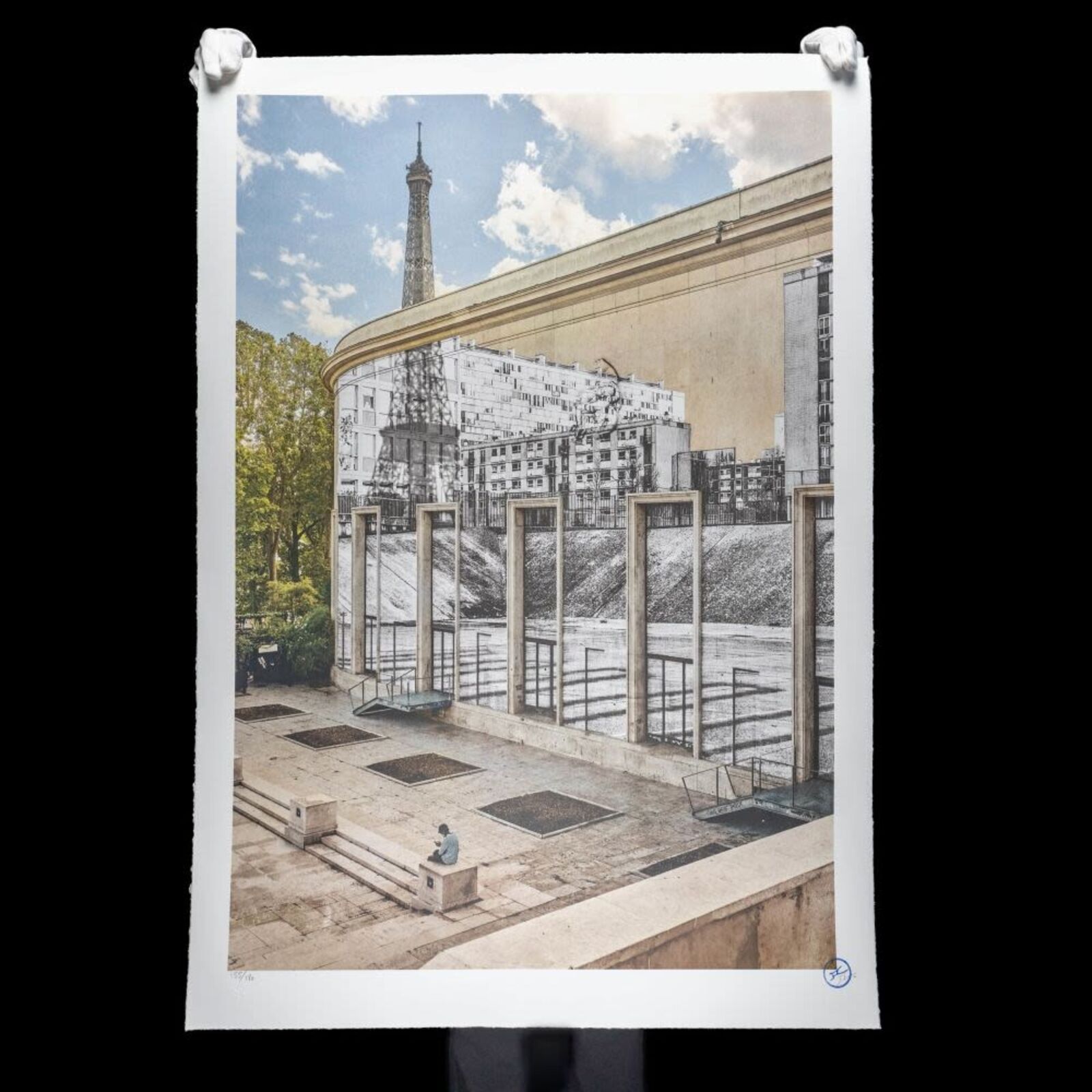 A man sitting on a bench in front of a mural of the Eiffel Tower.