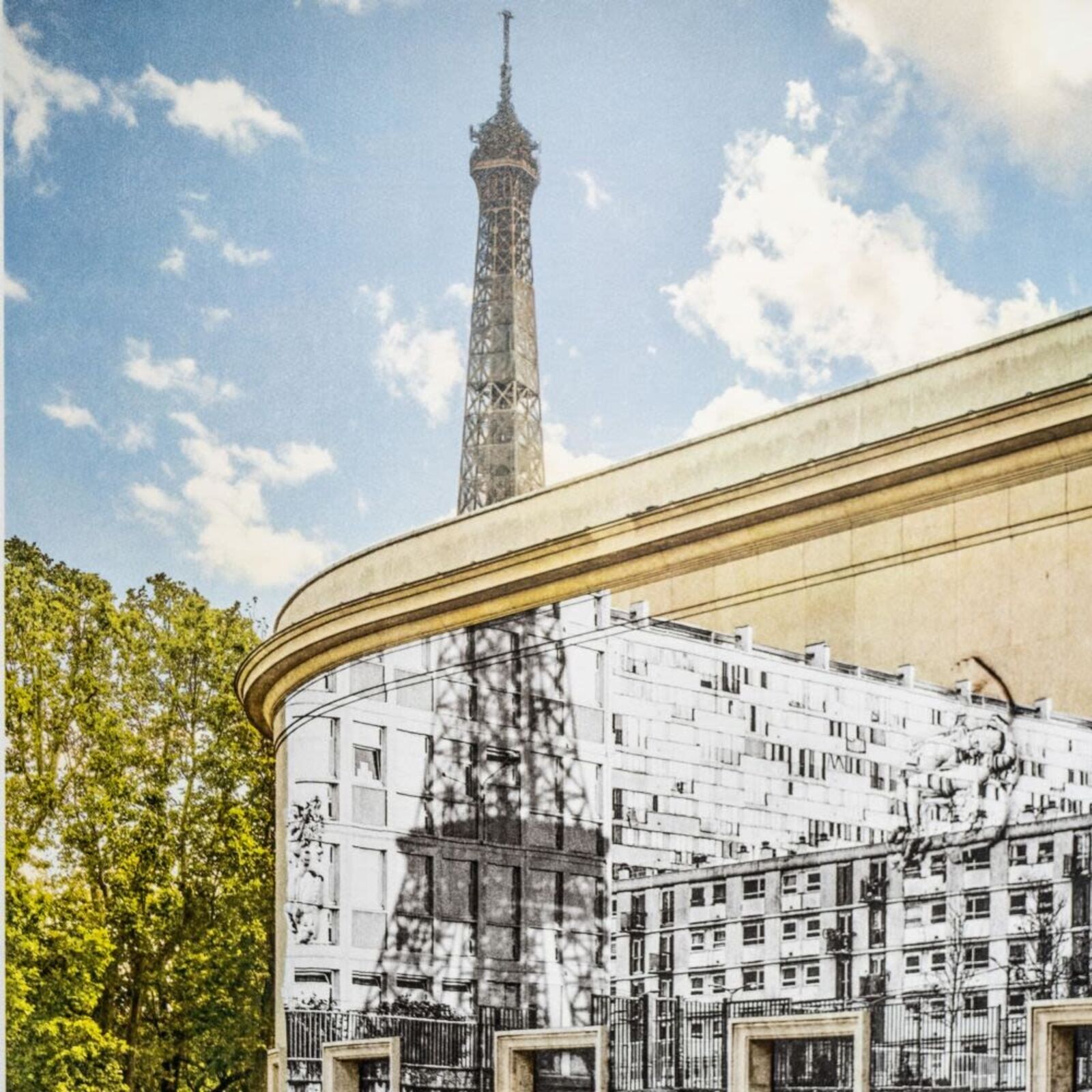 A man sitting on a bench in front of a mural of the Eiffel Tower.